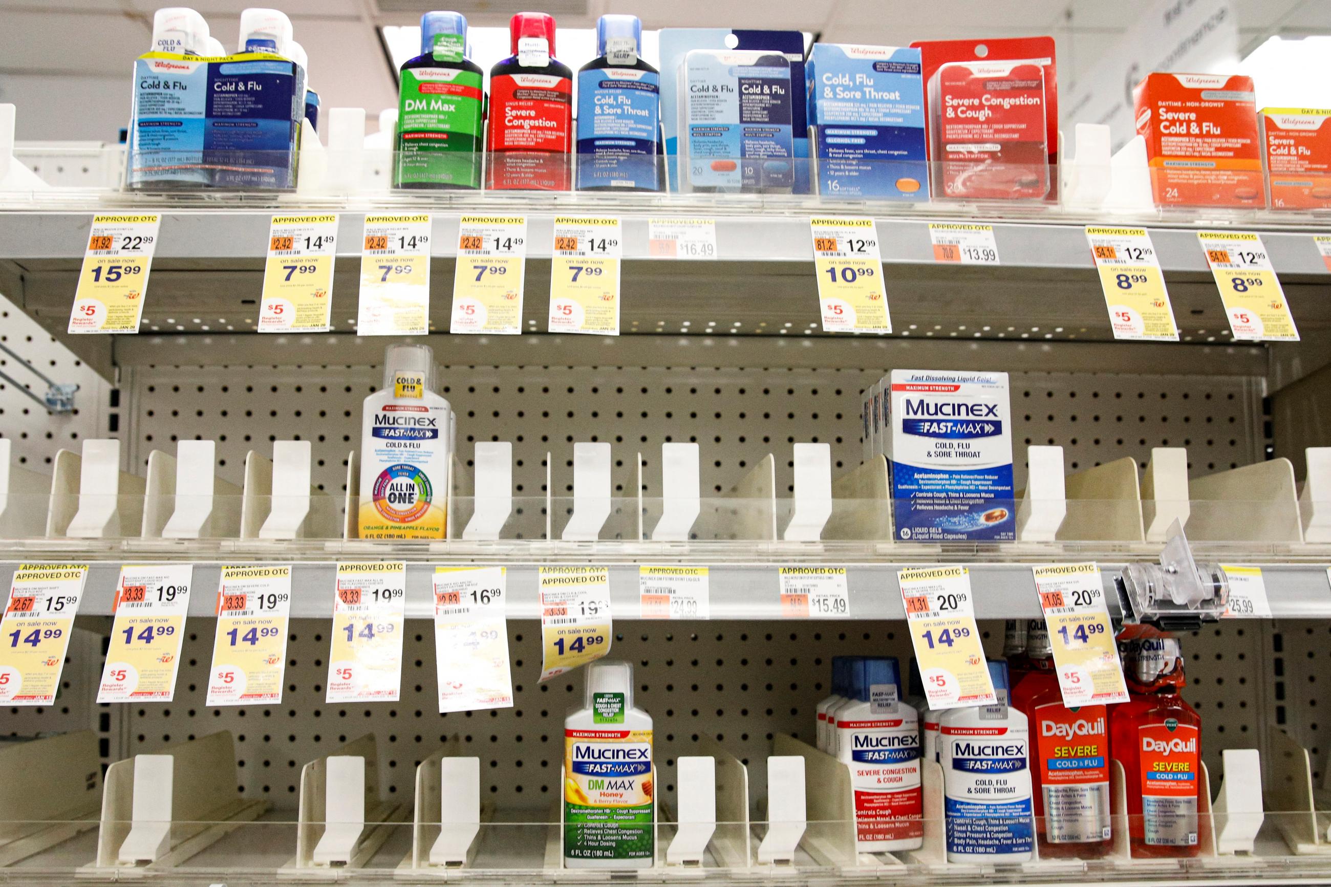 Nearly empty shelves drug store shelves on which there are only a few remaining cold medicines in blue, green, and red bottles.