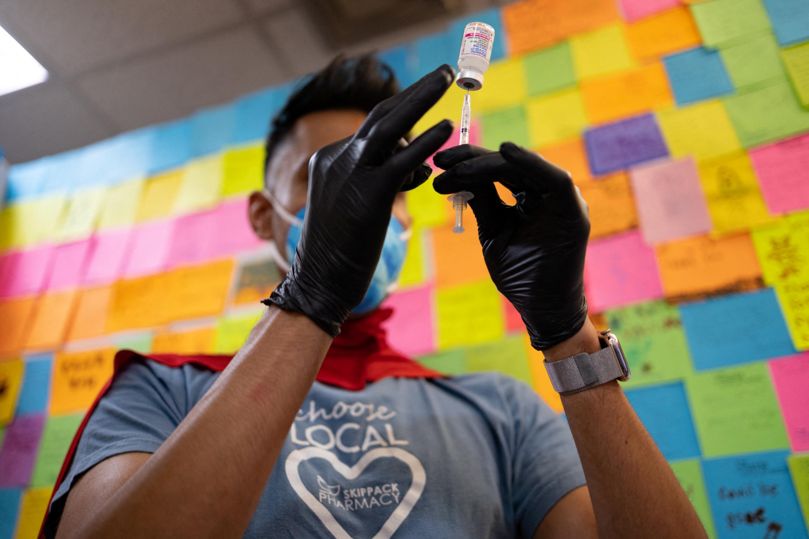 Dr. Mayank Amin, in a red superhero cape and gray t-shirt with a white heart, prepares a Moderna COVID-19 vaccine for a child under five-years-old, at Skippack Pharmacy in Schwenksville, Pennsylvania, on June 20, 2022.