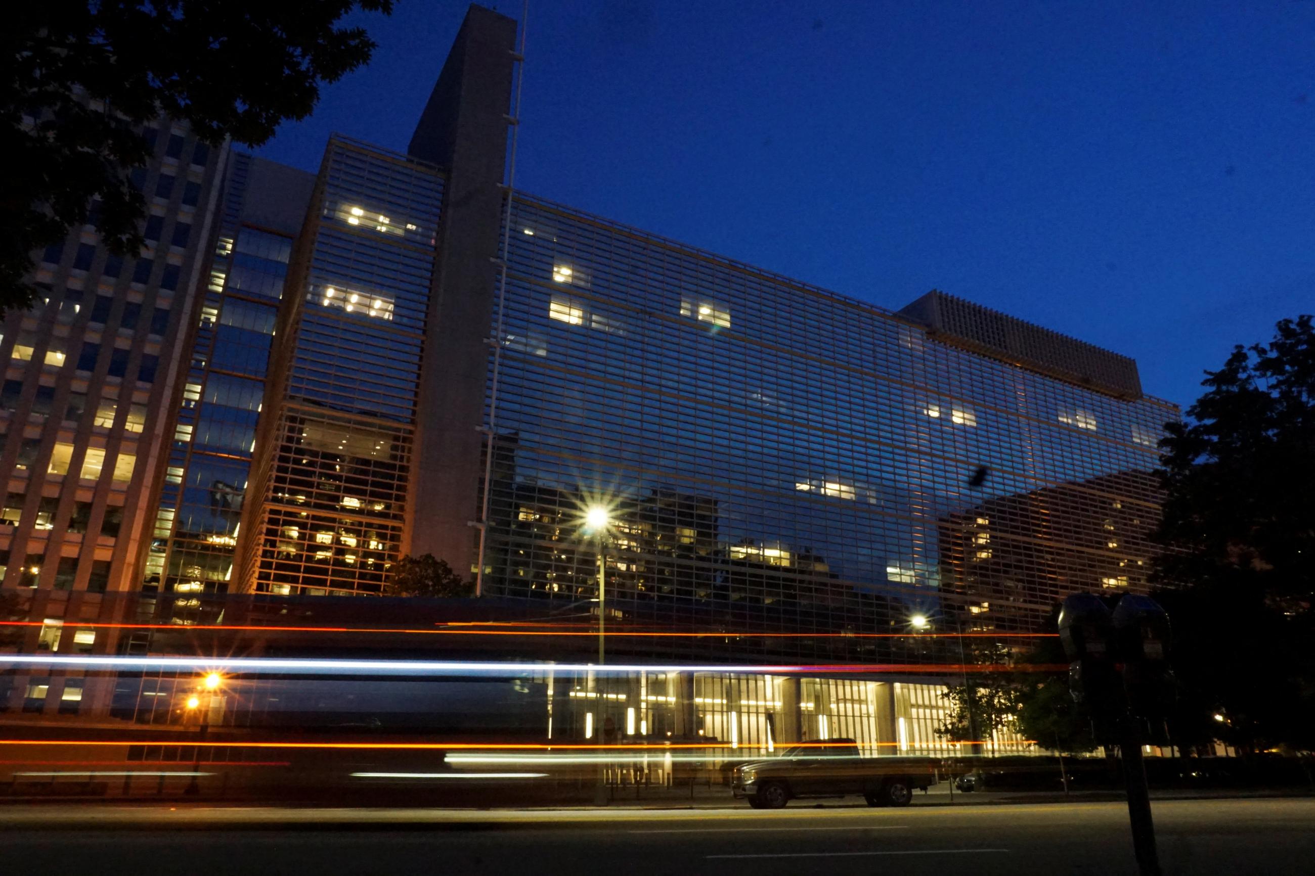 a long exposure image captures cars passing the world bank building (a mid-rise building) in Washington DC, at night