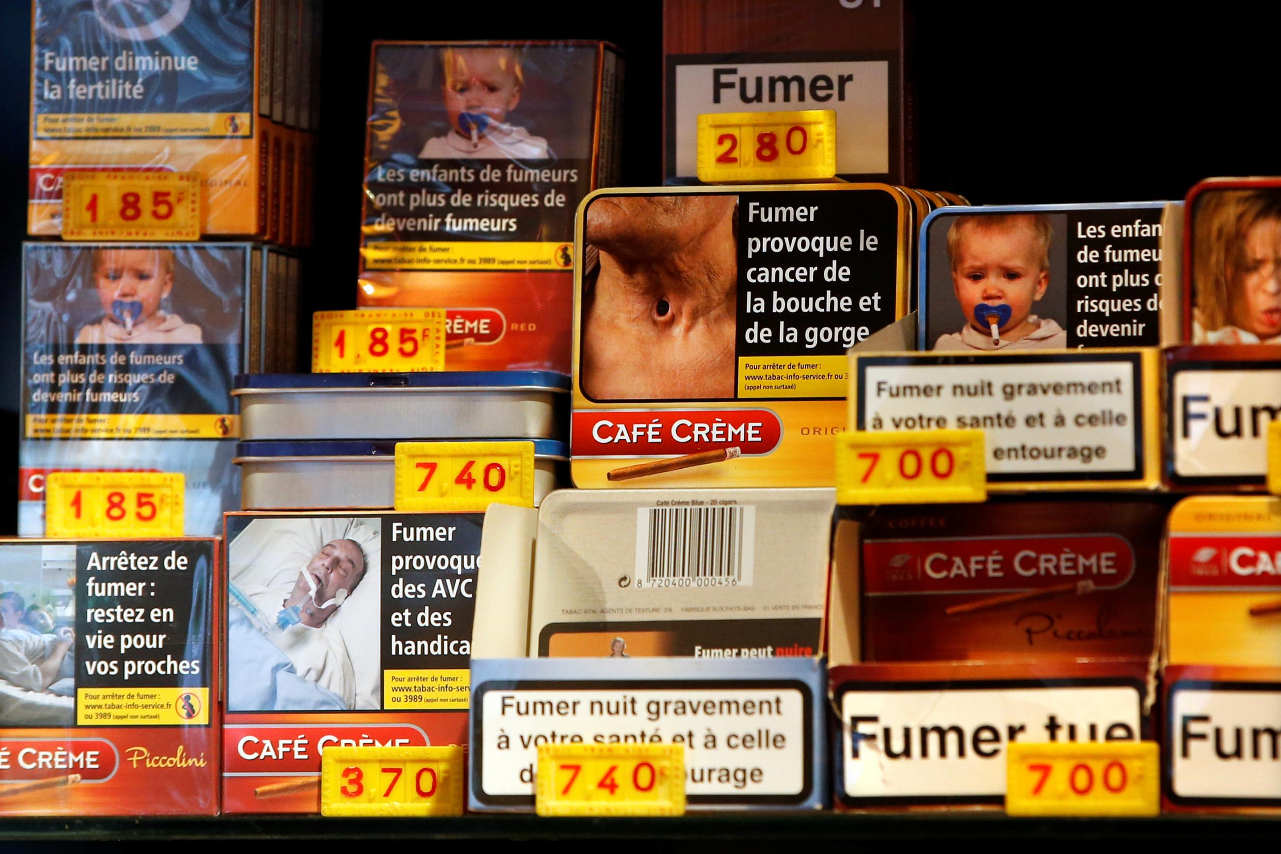 Small packs of cigars are stacked on top of each other in a display case at a tobacco store in France. The packaging shows graphic images of cancers and birth defects to discourage customers from purchasing the products. 