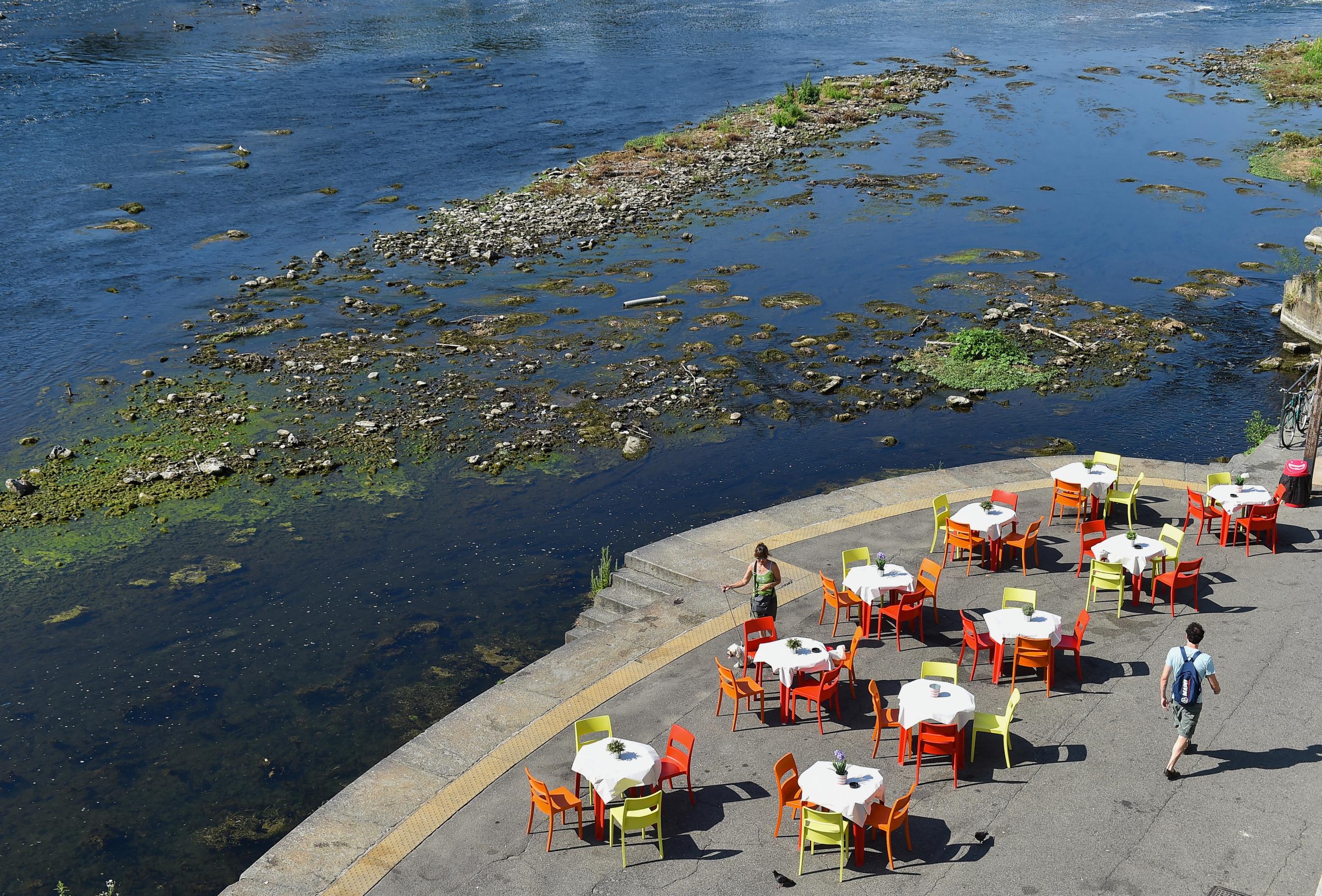 colorful restaurant tables with white tablecloth are seen alongside the Po's dry riverbed, in Turin, Italy