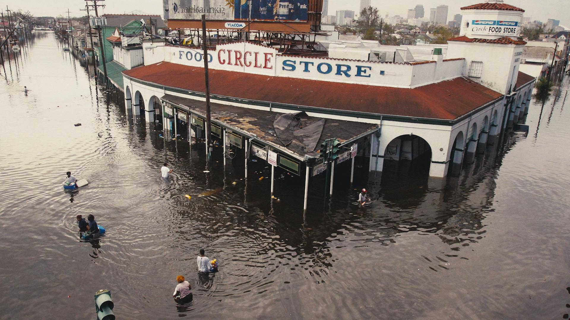 A store in the film director's neighborhood in New Orleans waist-deep in flood waters. People move through the water nearby.