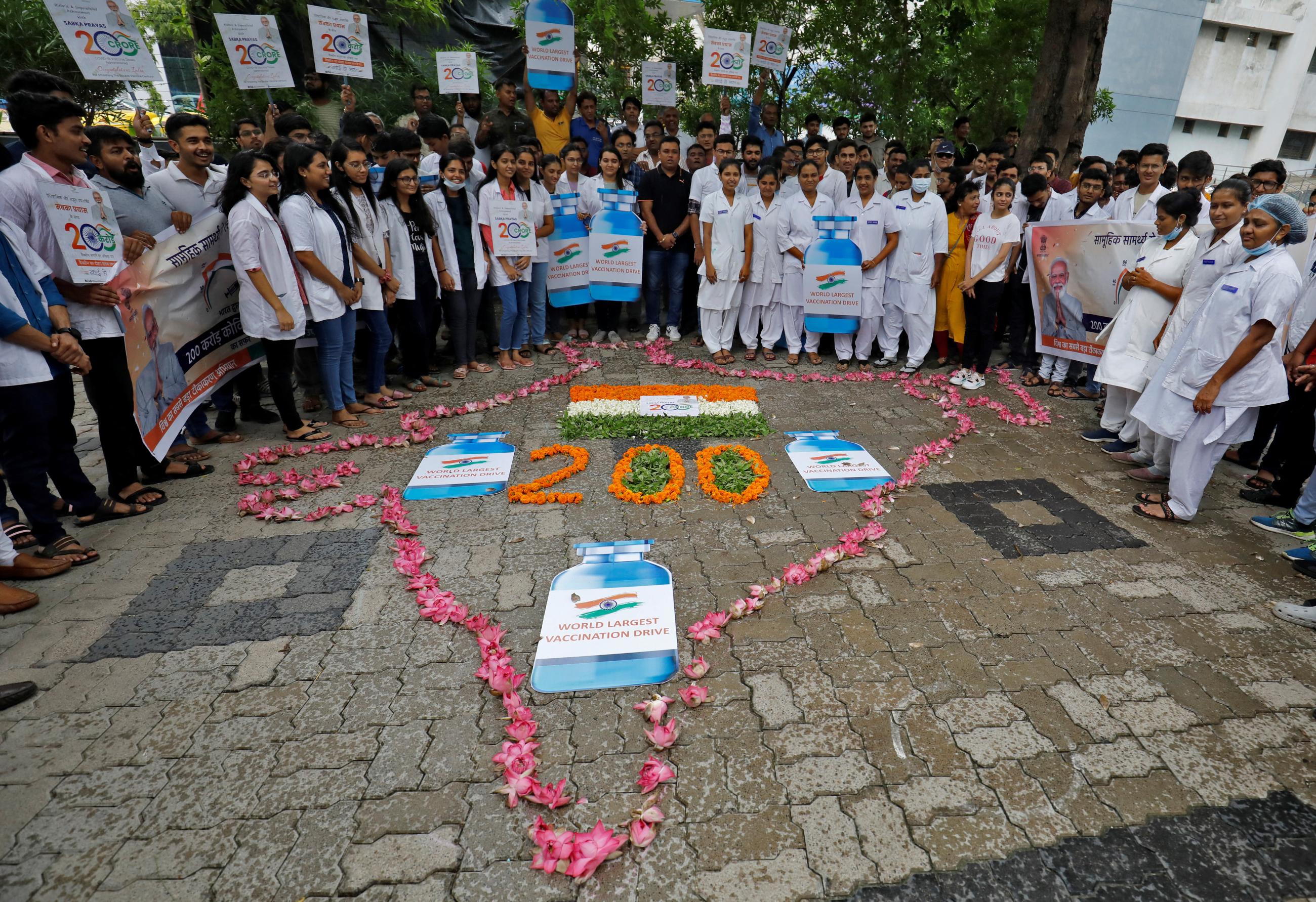 Medical staff and students stand around a design on the ground, made of pink flower blossoms in the shape of the country of India, to celebrate India administering 2 billion doses of COVID-19 vaccines at a hospital in Ahmedabad, India, on July 17, 2022. REUTERS/Amit Dave