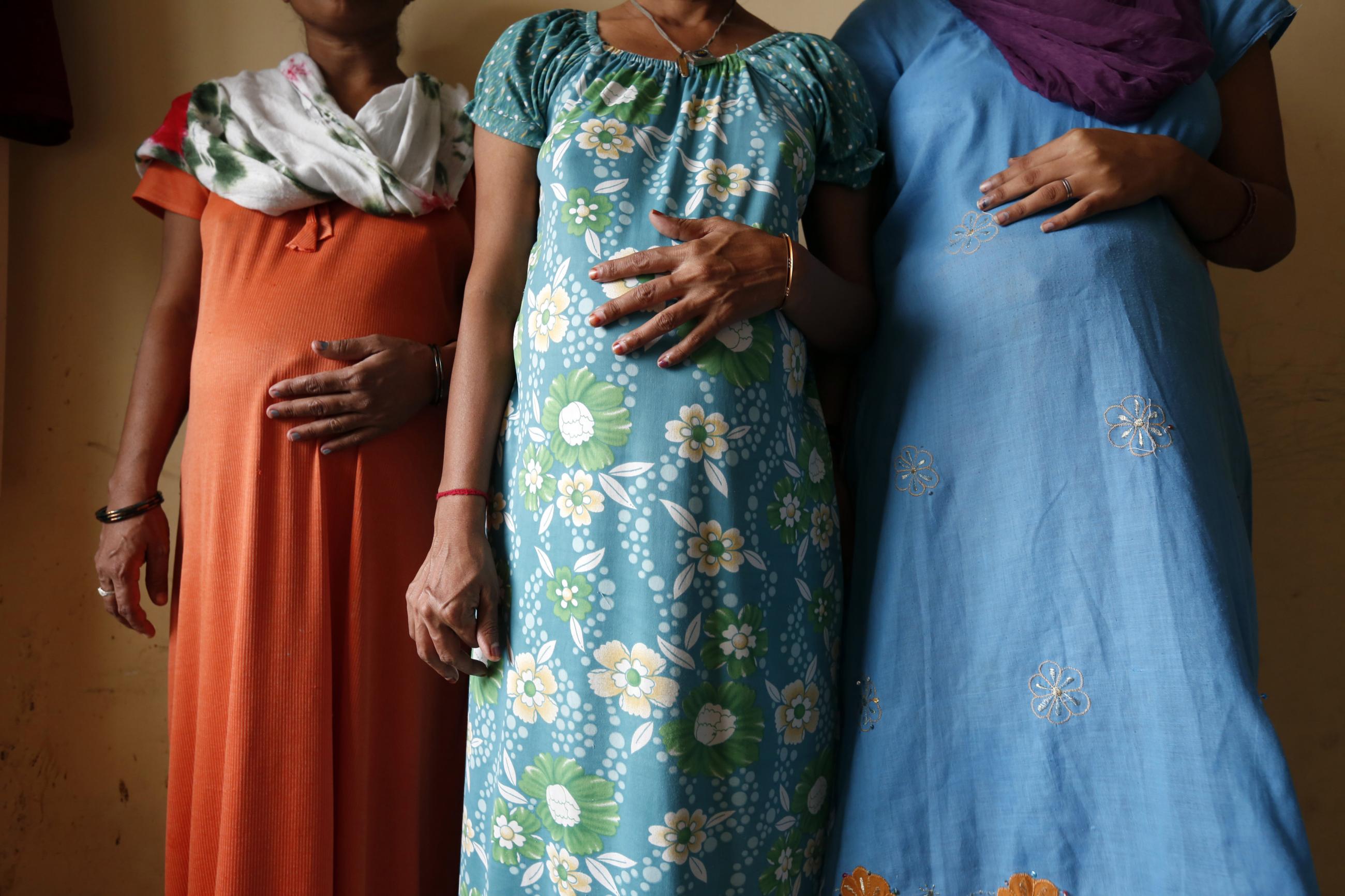Three pregnant women—Daksha, Renuka, and Rajia—all surrogate mothers, pose wearing colorful dresses for a photo in Anand, a town about 70 km (44 miles) south of Ahmedabad, India,
