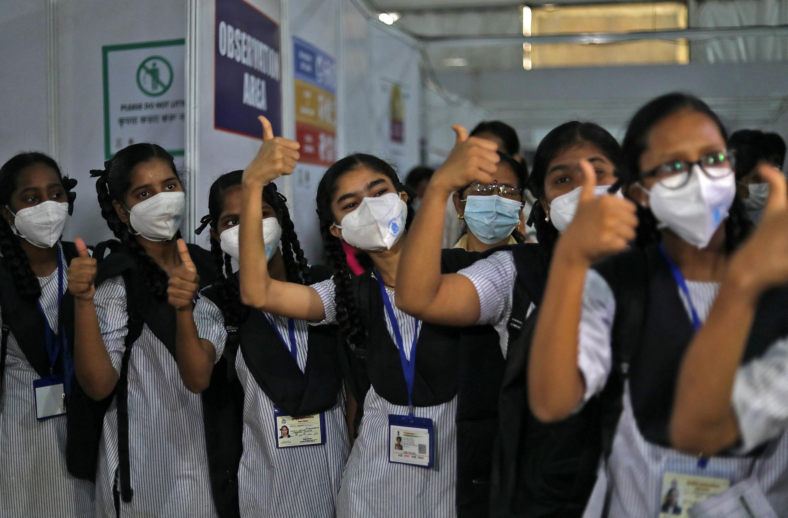 Girls dressed in white and blue striped uniforms with black scarves gesture after receiving a dose of Bharat Biotech's COVID-19 vaccine, Covaxin, during a vaccination drive for children aged 15-18 in Mumbai, India, on January 3, 2022. REUTERS/Niharika Kulkarni
