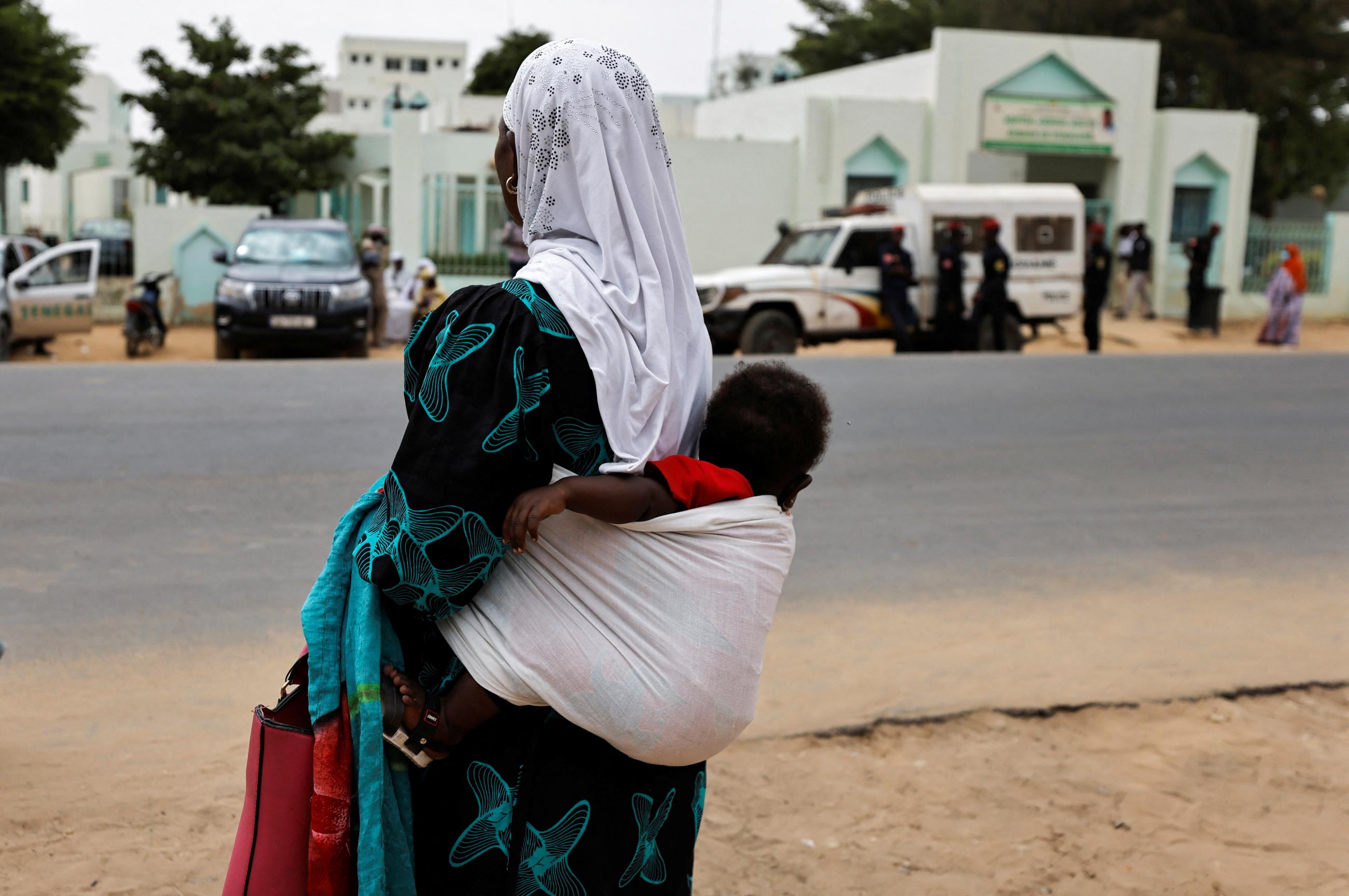 A woman carries her child as she stands in front of the hospital where new-born babies died in a fire at the neonatal section, in Tivaouane, Senegal May 26, 2022.