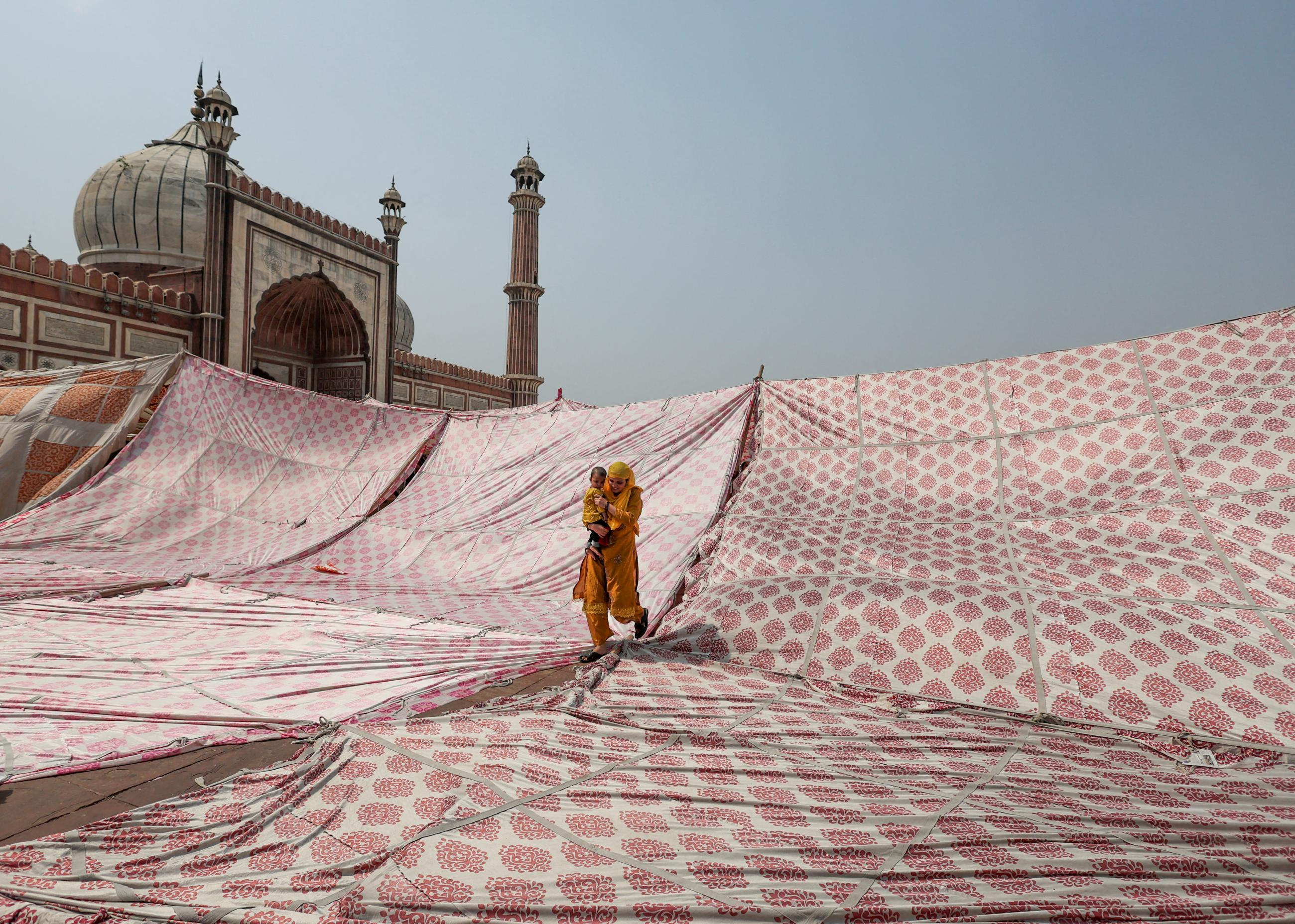 A Muslim woman and child leave after offering prayers during Jumat-ul-Vida, the last Friday of the holy fasting month of Ramadan, at Jama Masjid in the old quarters of Delhi, India, April 29, 2022. 