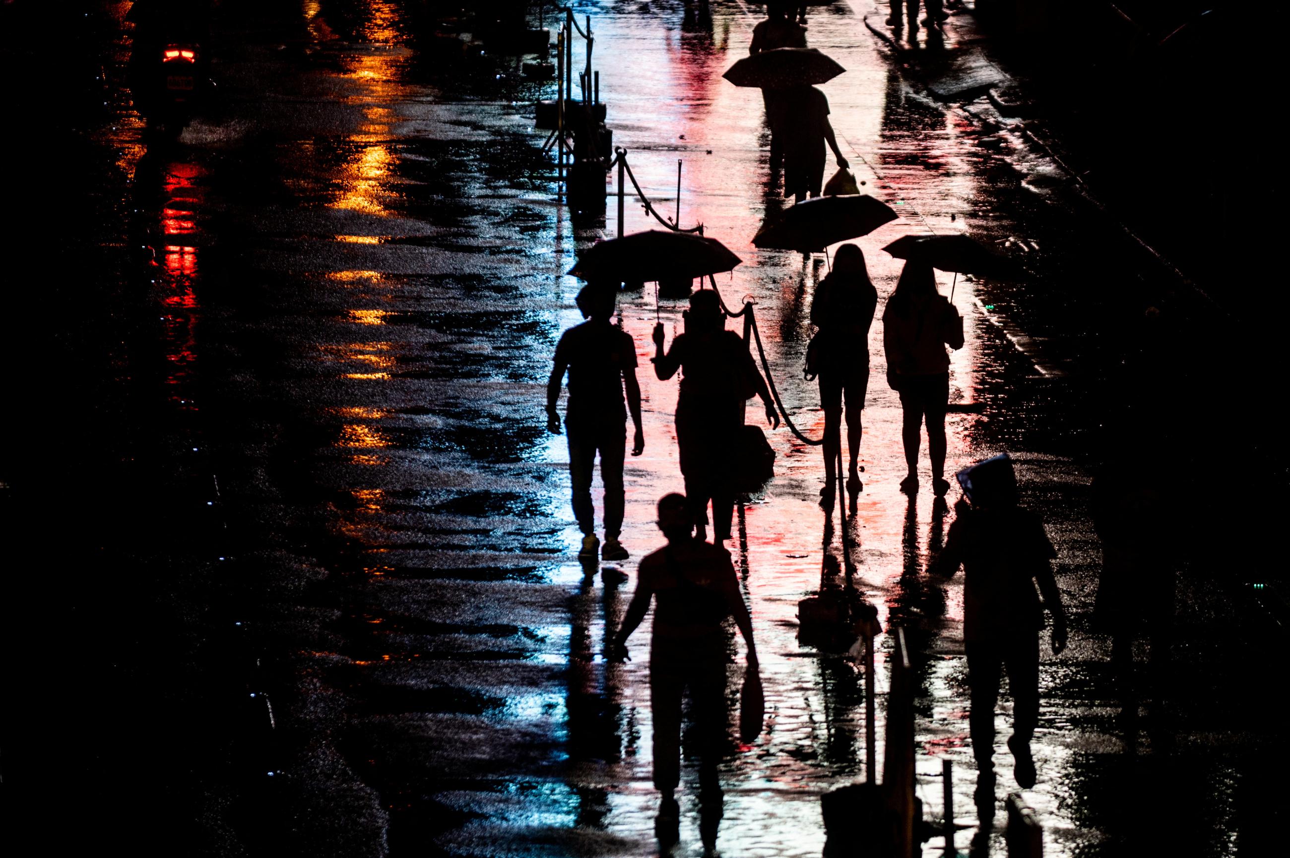 People walk in the rain outside a church in Manila, Philippines, October 25, 2022.