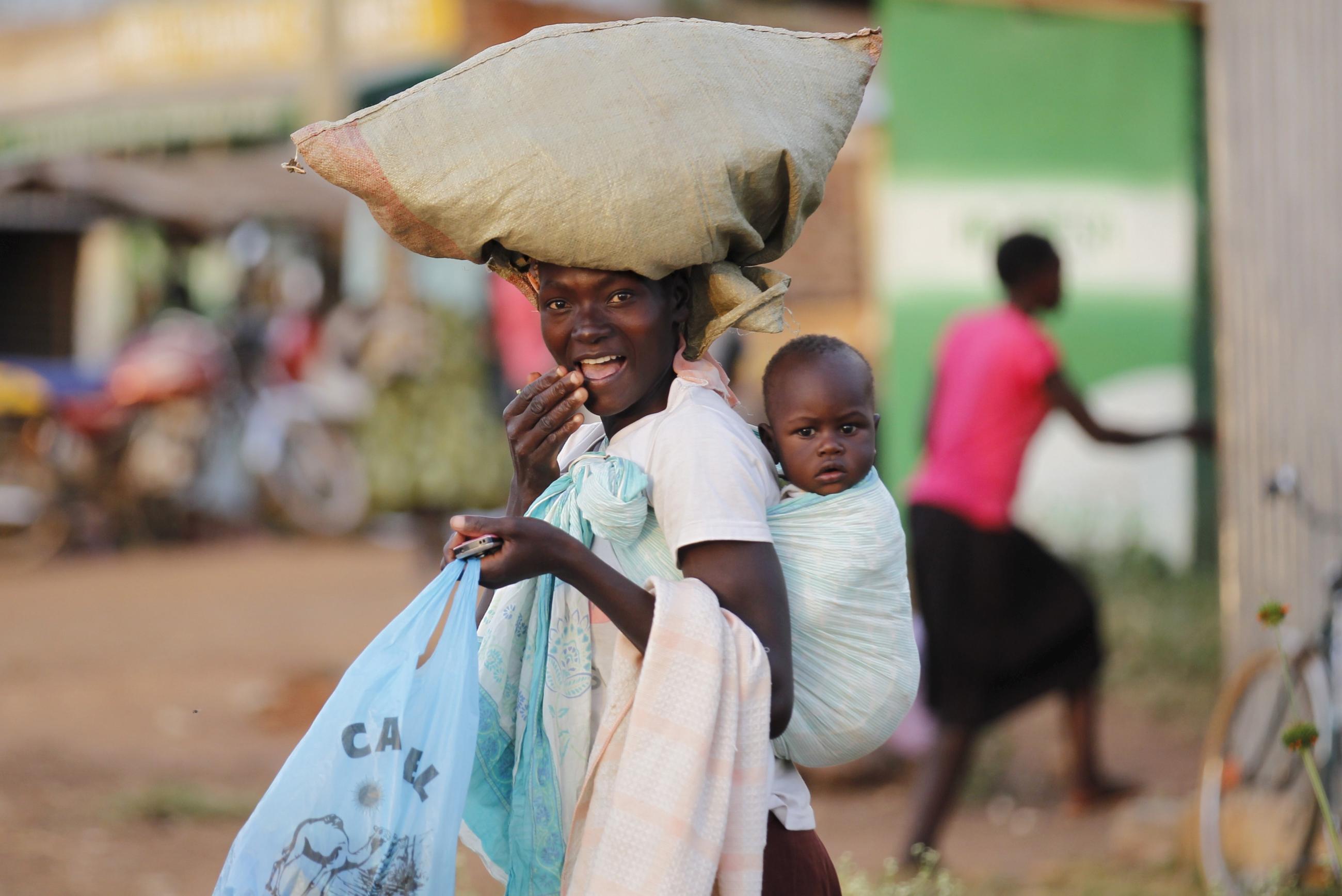 A woman carries a child and a bag on her head at the trading center in Nyang'oma Kogelo, west of Kenya'