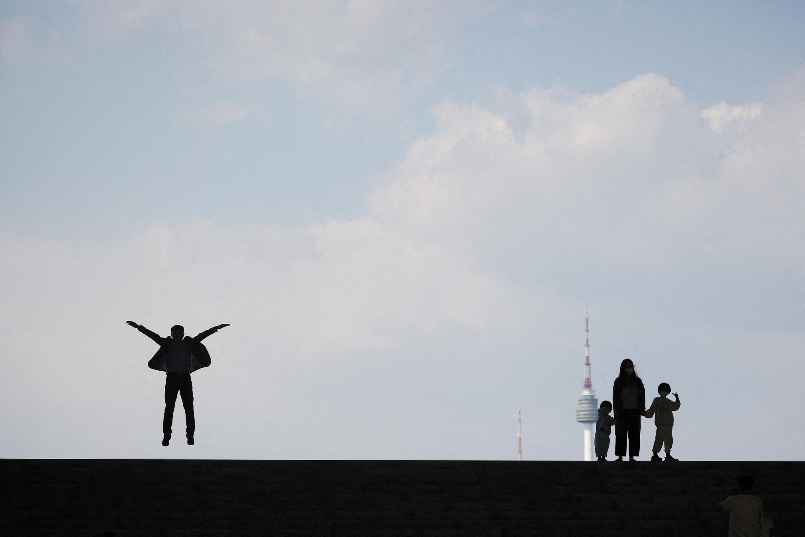 People wearing masks to prevent COVID transmission pose for photographs on a spring day in Seoul, South Korea, May 2, 2022.