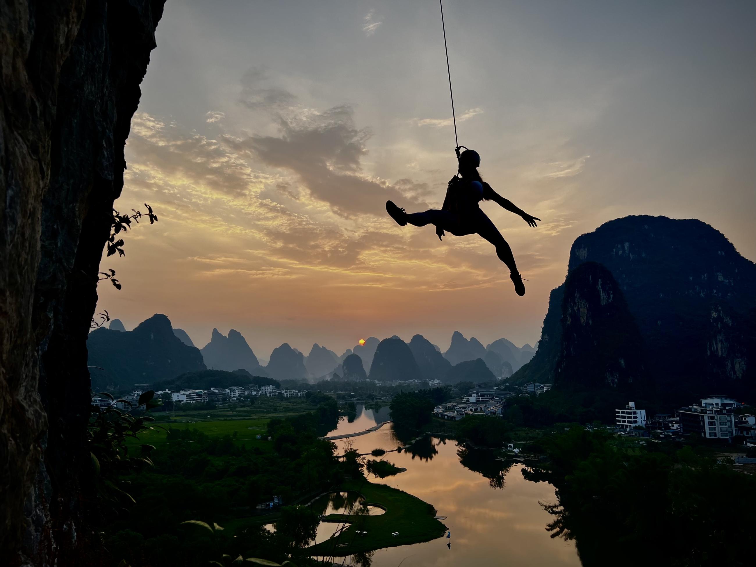 Min being lowered from a climb during her pregnancy in Yangshuo, China with the Li River in the background, 2022.