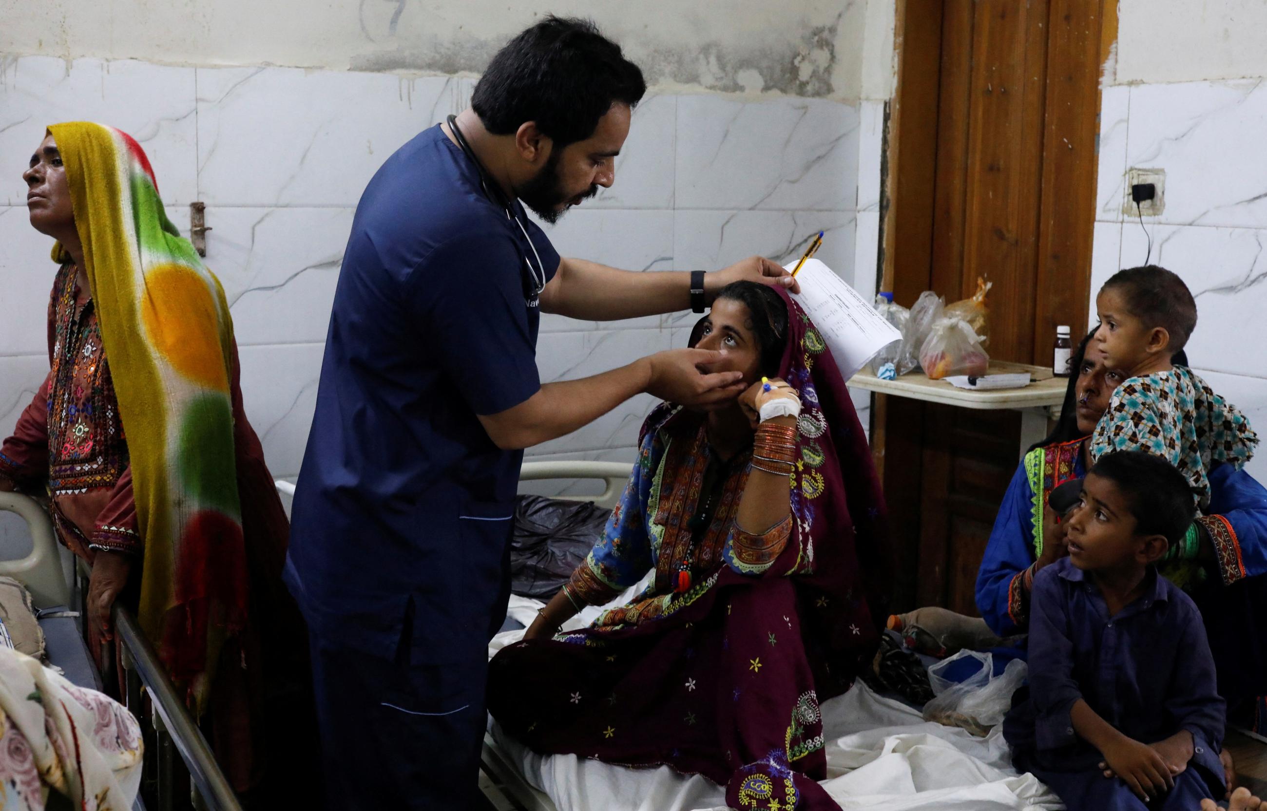 Naveed Ahmed, a doctor, gives medical assistance to flood-affected girl, Hameeda, suffering from malaria, at Sayed Abdullah Shah Institute of Medical Sciences in Sehwan, Pakistan September 29, 2022.