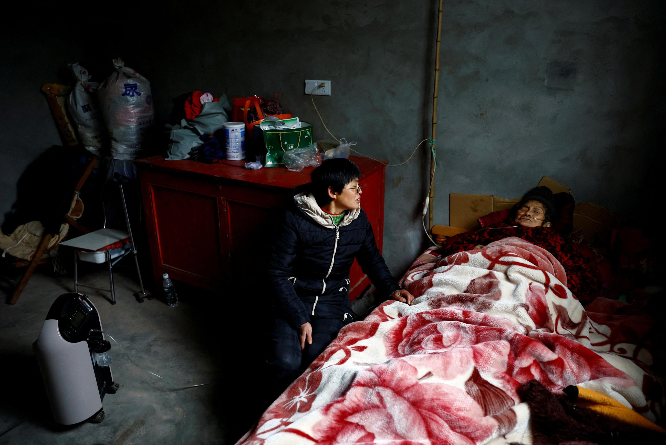 Liao Xiaofeng sits by an oxygen contractor and her mother Chen Lifen, upon returning from a clinic, after strict measures to curb COVID-19 were removed in Ziyang, China, on December 29, 2022.