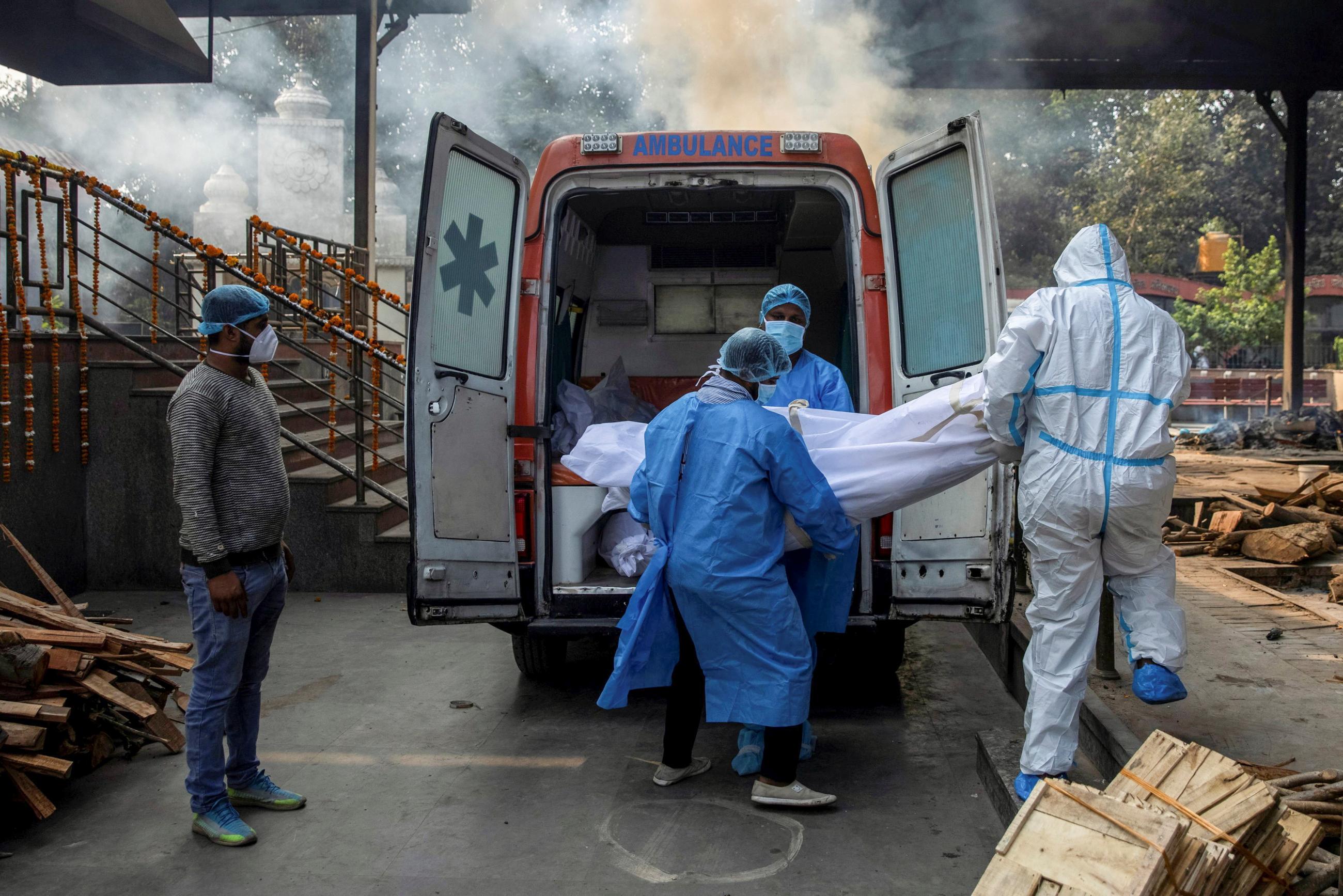 Health workers and a relative carry the body of a man, who died due to COVID-19, from an ambulance to a crematorium in New Delhi, India, November 13, 2020.