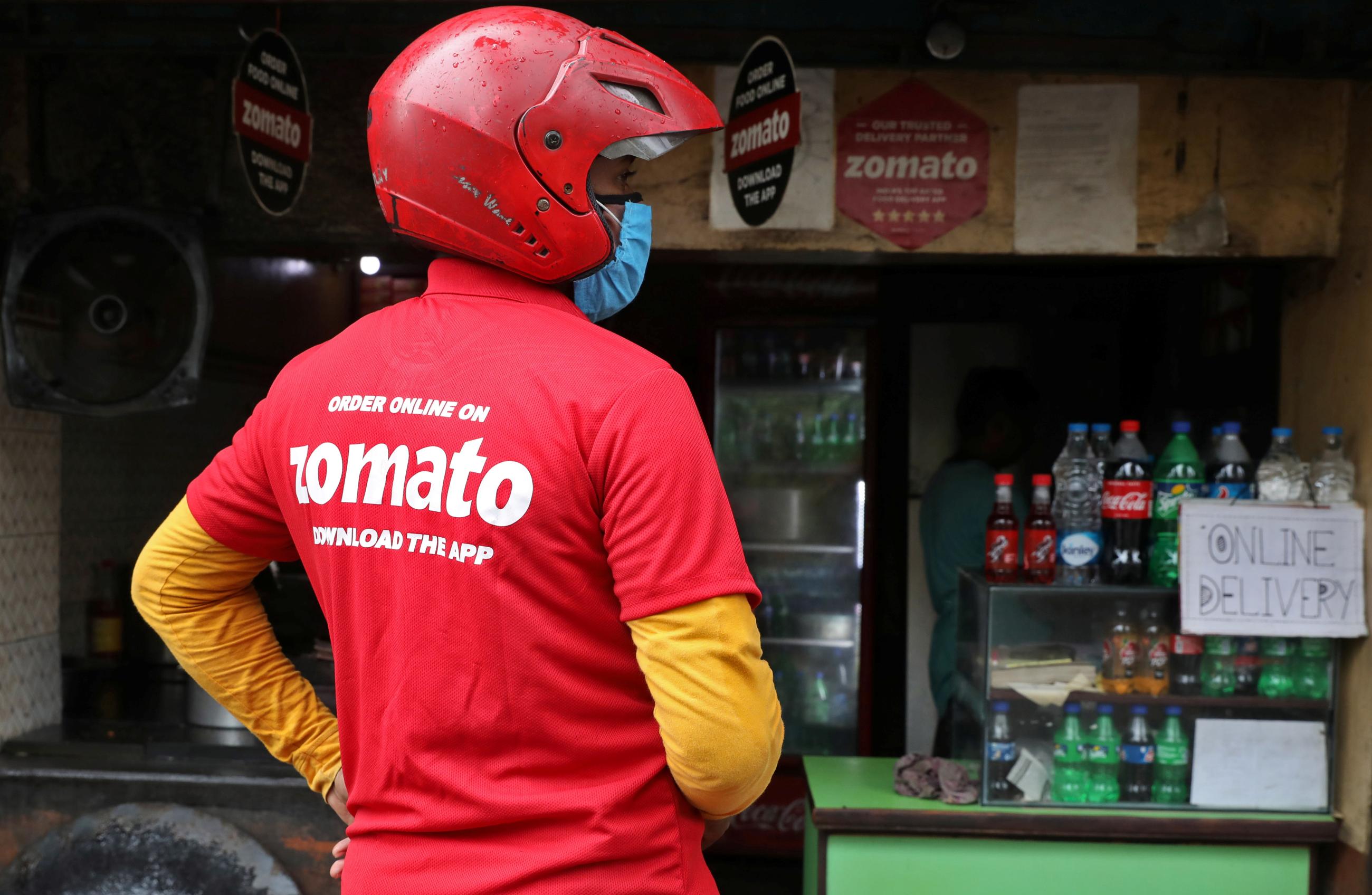 A delivery worker of Zomato, an Indian food-delivery startup, wearing a face mask waits to collect order outside an eatery in Kolkata, India, July 13, 2021.