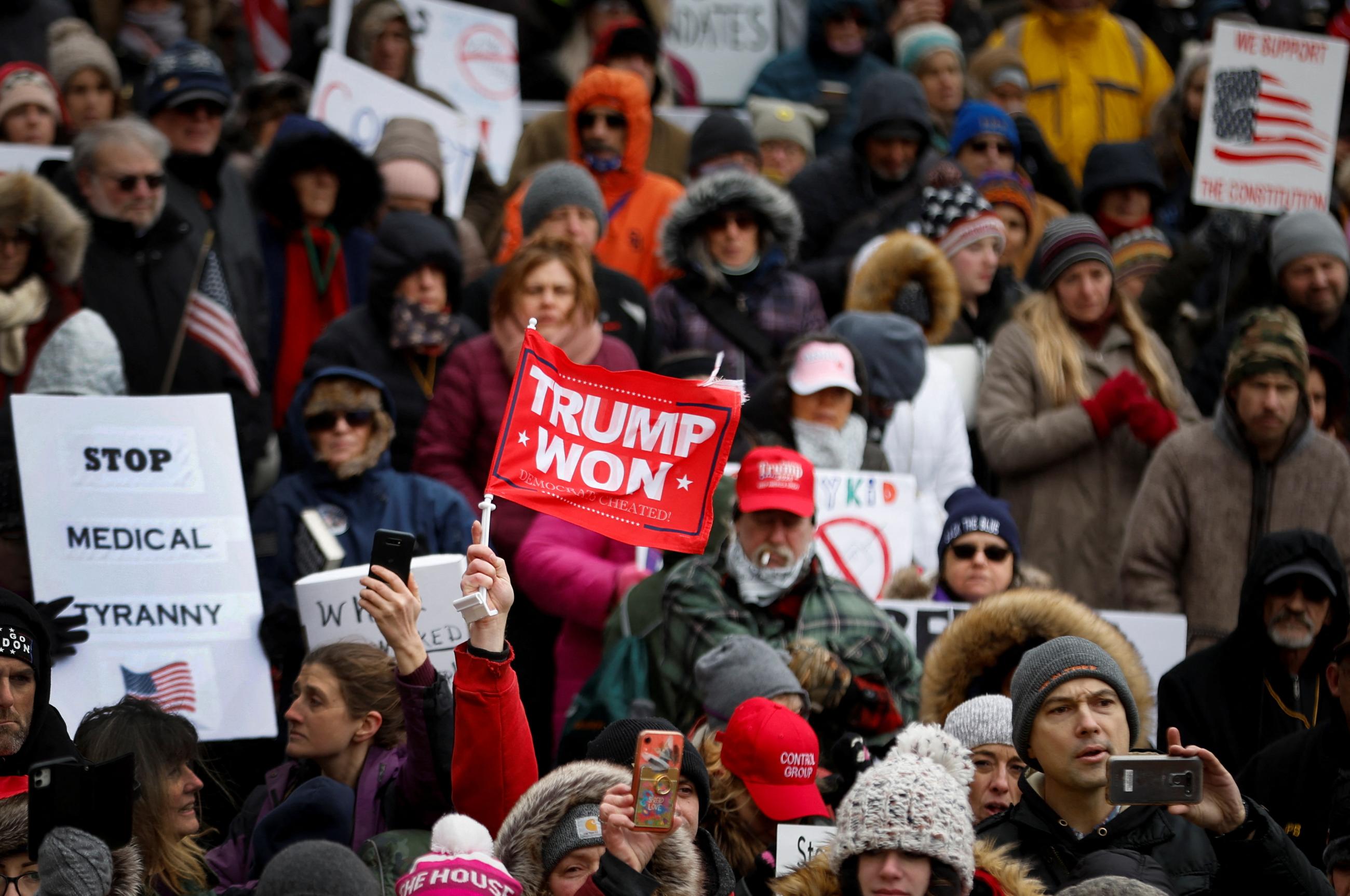 A man holds up a flag reading "Trump Won" in the crowd as protestors demonstrate outside the New York State Capitol in Albany against mandates for the vaccines against the coronavirus disease (COVID-19), January 5, 2022. 