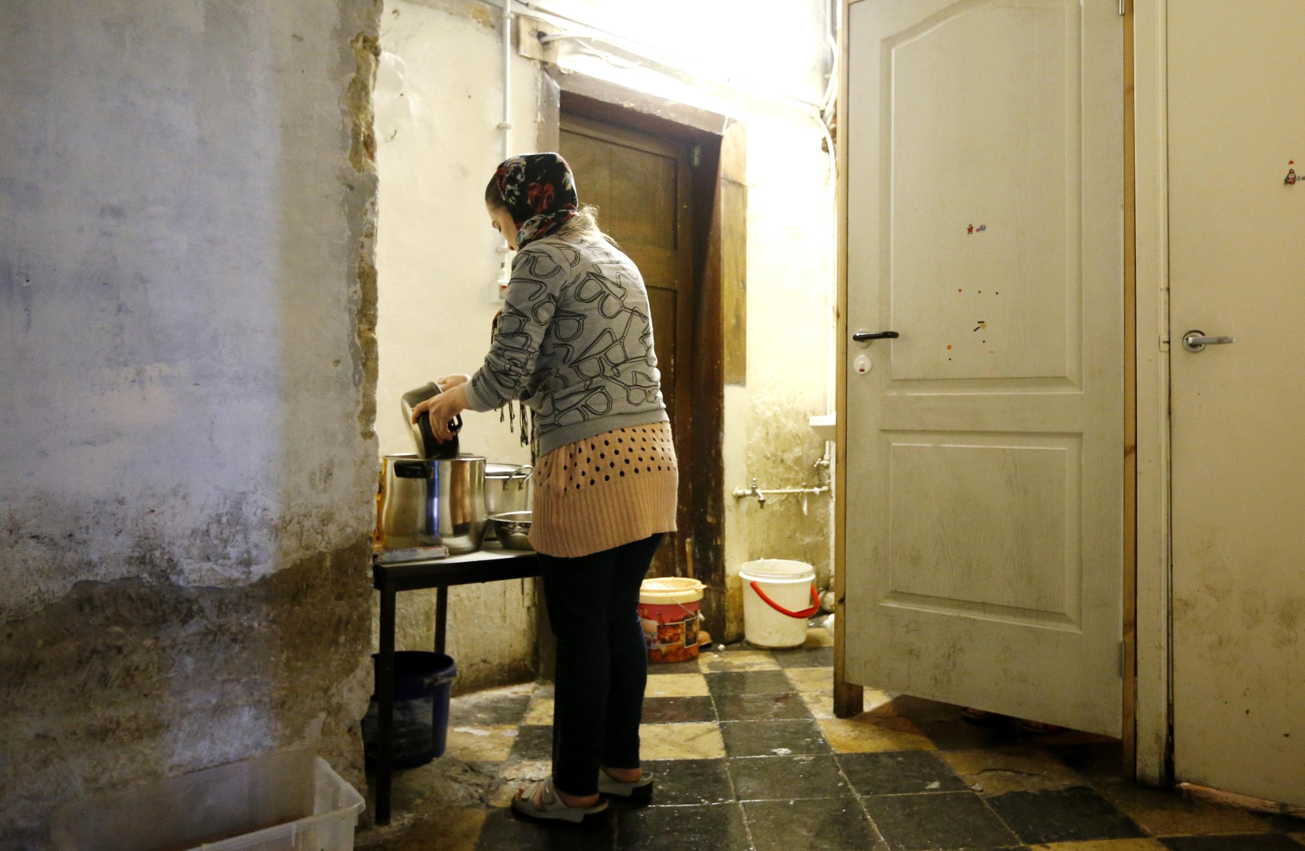 An Afghan woman washes dishes in the toilet of the Church of Saint John the Baptist at the Beguinage in central Brussels, which is occupied by asylum seekers, on January 30, 2014