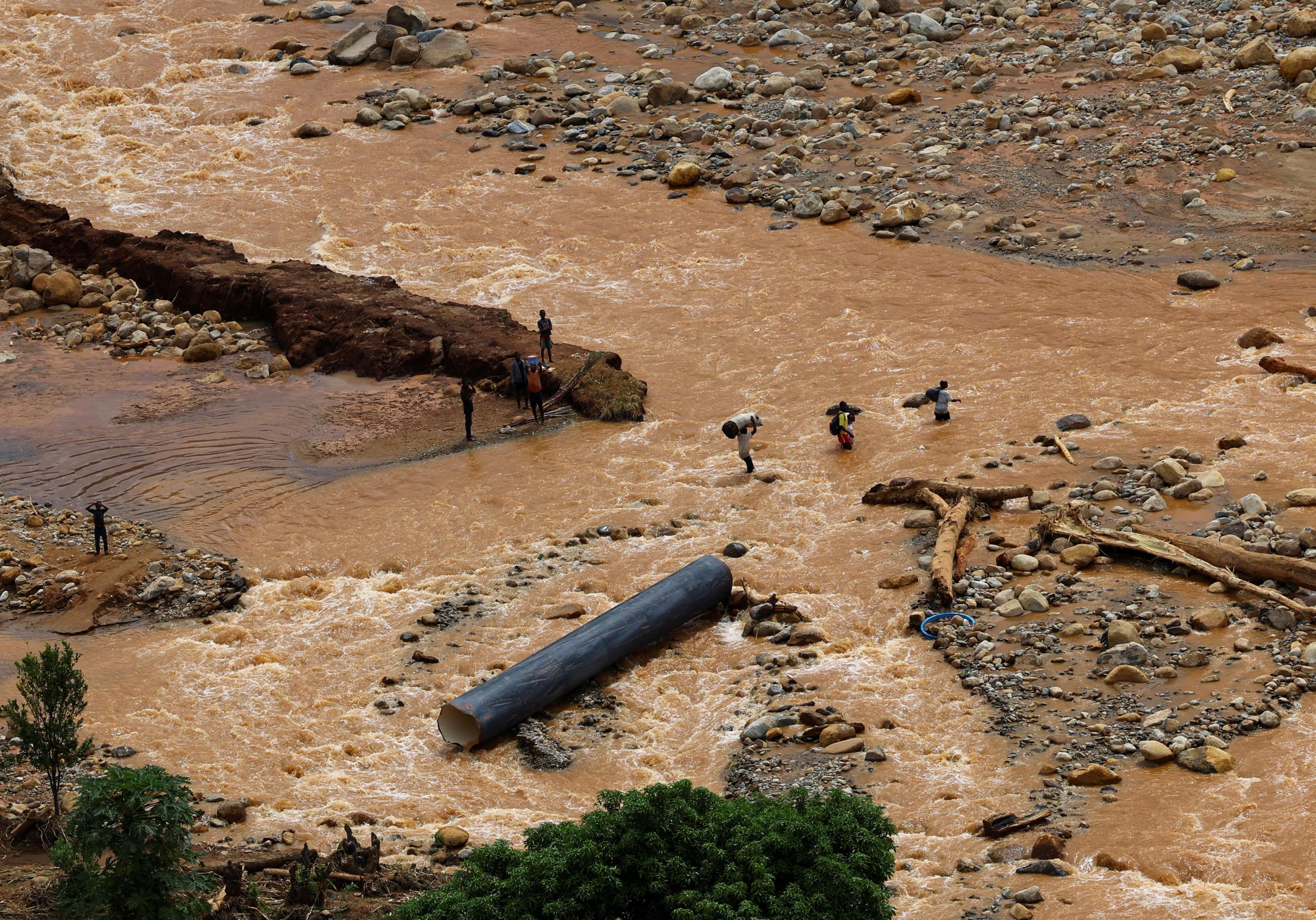 People cross a flooded area in Muloza on the border with Mozambique after the aftermath of Tropical Cyclone Freddy, around one hundred kilometers outside Blantyre, Malawi, on March 18, 2023.