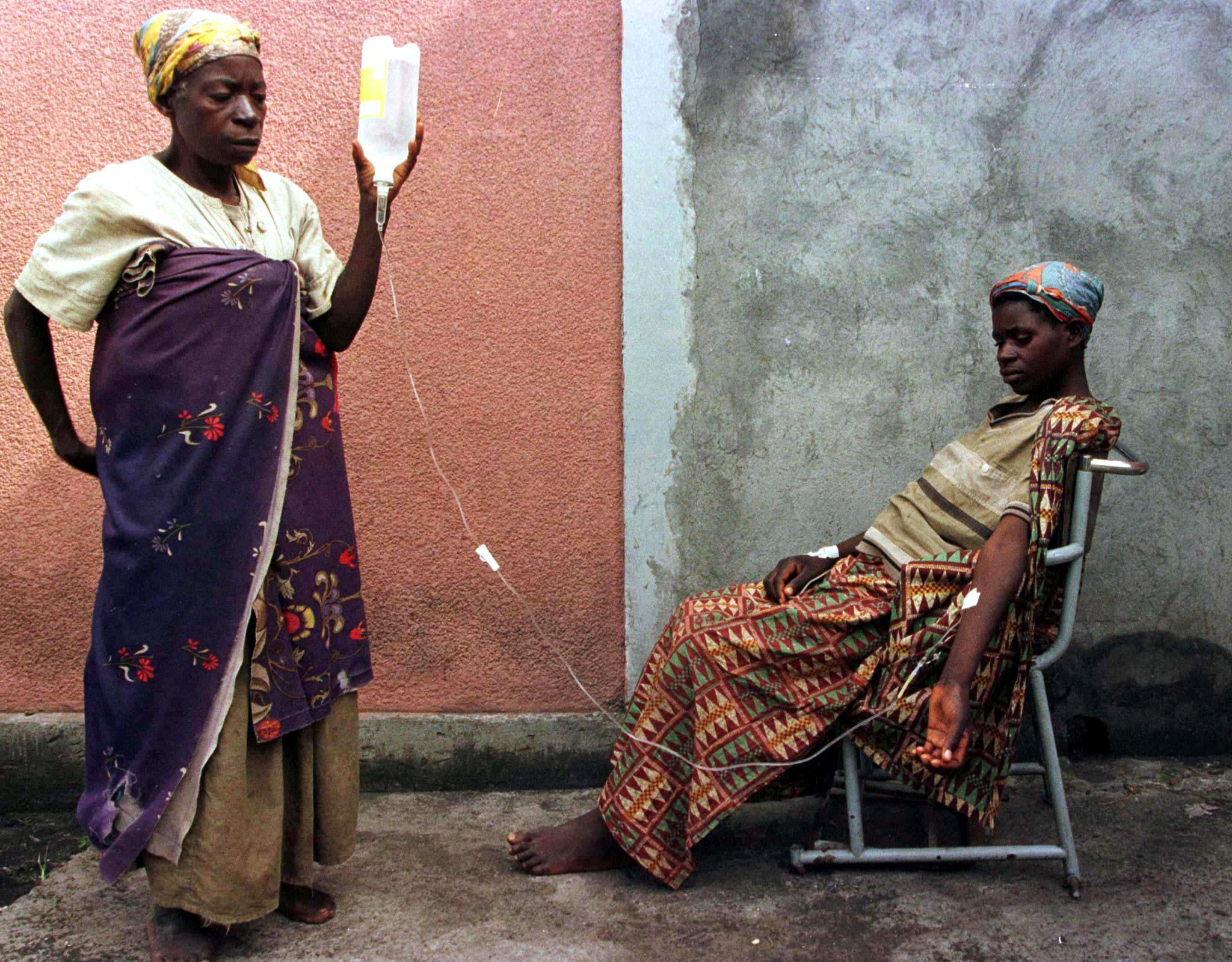 A Rwandan Hutu refugee woman helps her daughter with an IV at the local hospital in the town of Goma on November 17, 1996.