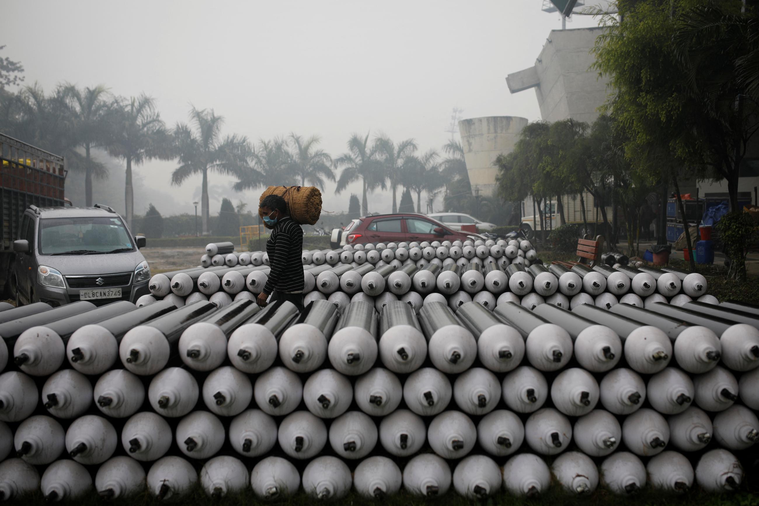 A laborer walks past the empty oxygen cylinders outside a coronavirus disease (COVID-19) care centre at an indoor sports complex amid the spread of the disease, in New Delhi, India, January 5, 2022.