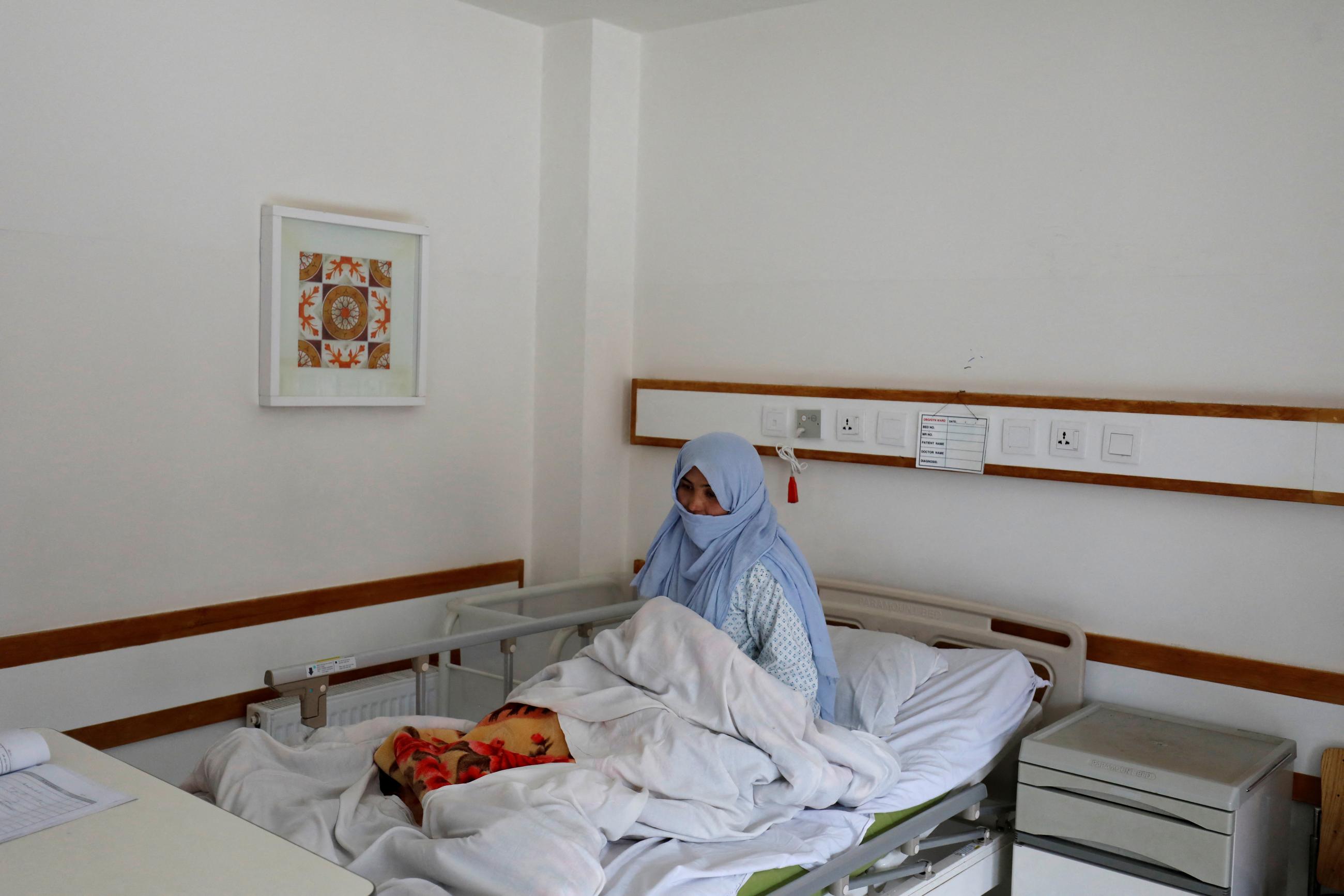 A woman sits on a hospital bed in Bamiyan, Afghanistan, March 02, 2023. Since taking over in 2021, Taliban authorities have barred women from universities and most charity jobs, but they have made exemptions in the healthcare sector