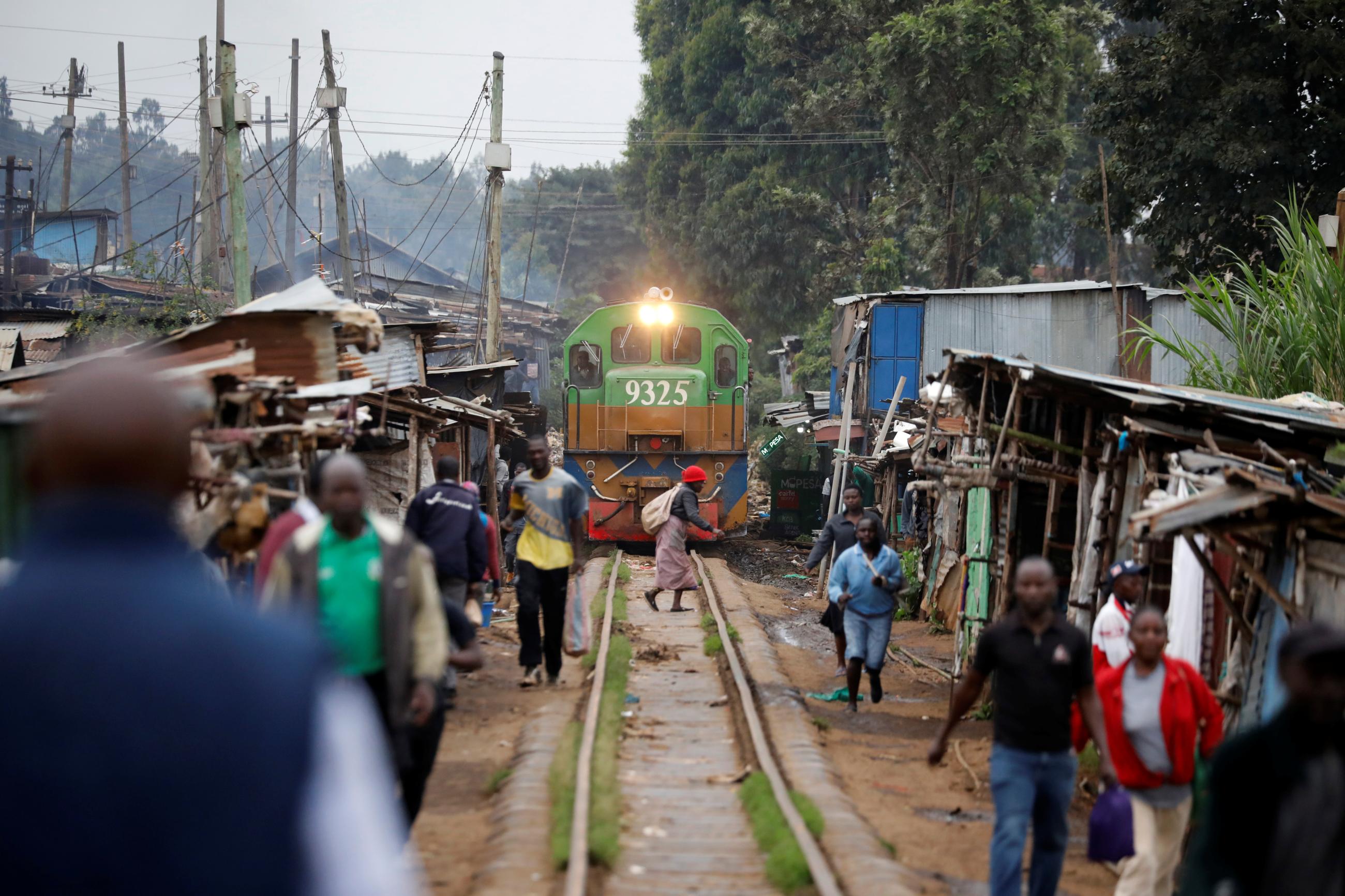 A woman crosses a railway track just as a train approaches a makeshift train station in the Kibera slum of Nairobi. 