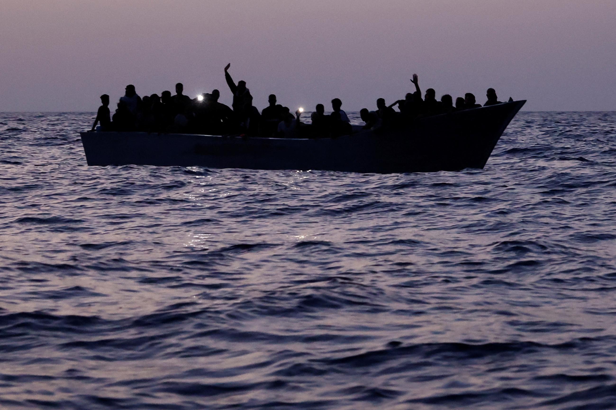 A boat full of migrants floats on the sea. 