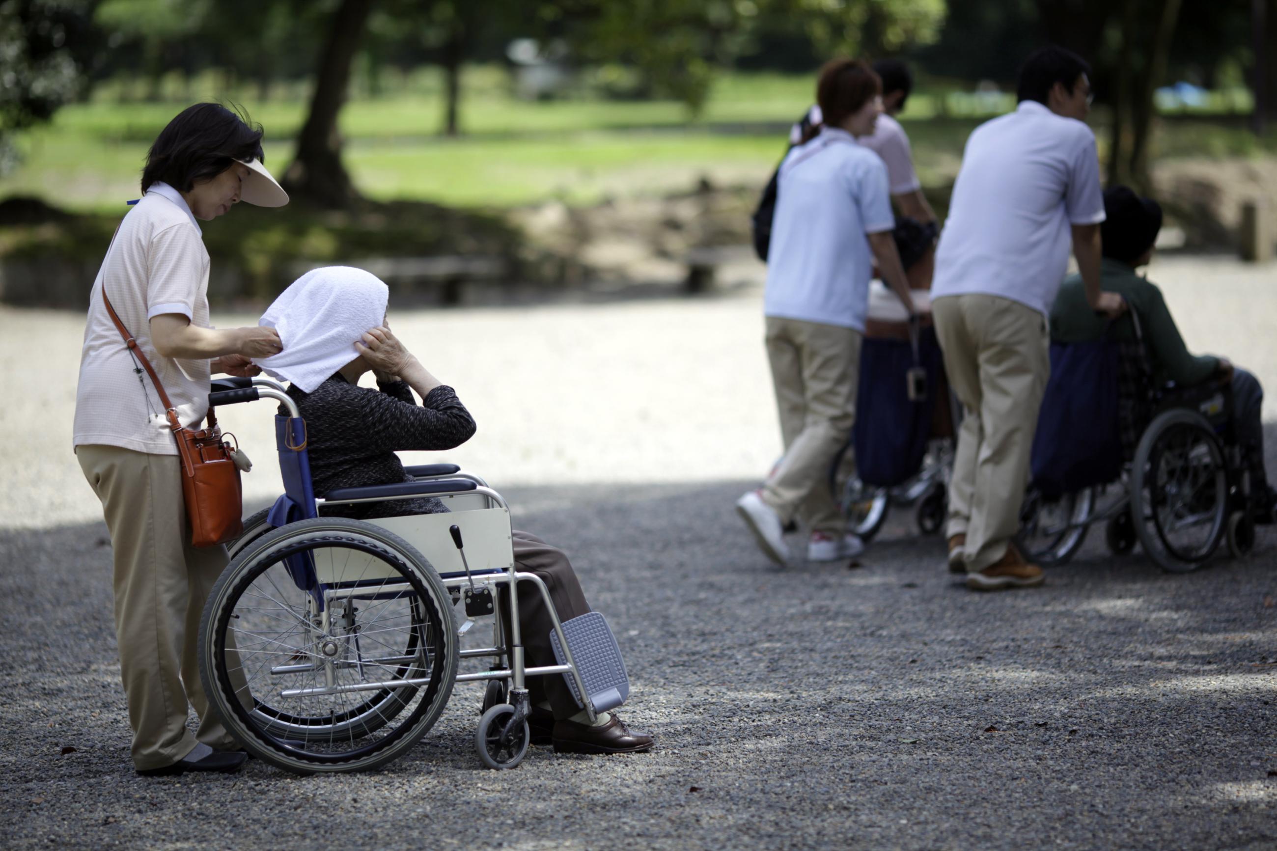 A woman helps an elderly woman in a wheelchair.