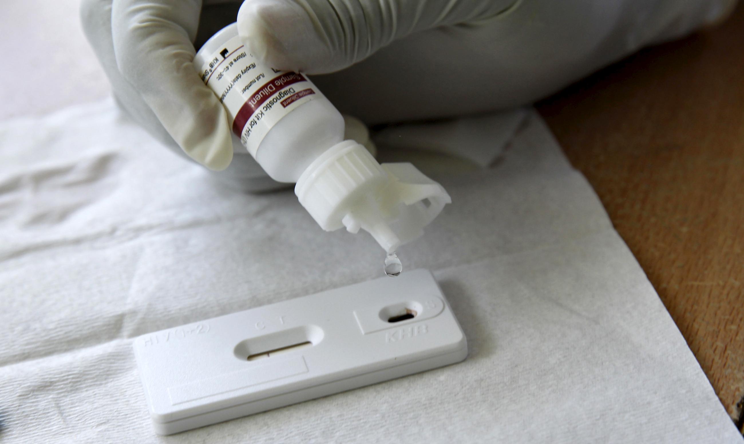 a counsellor, adds a reactor to a blood sample from a woman to test for HIV.