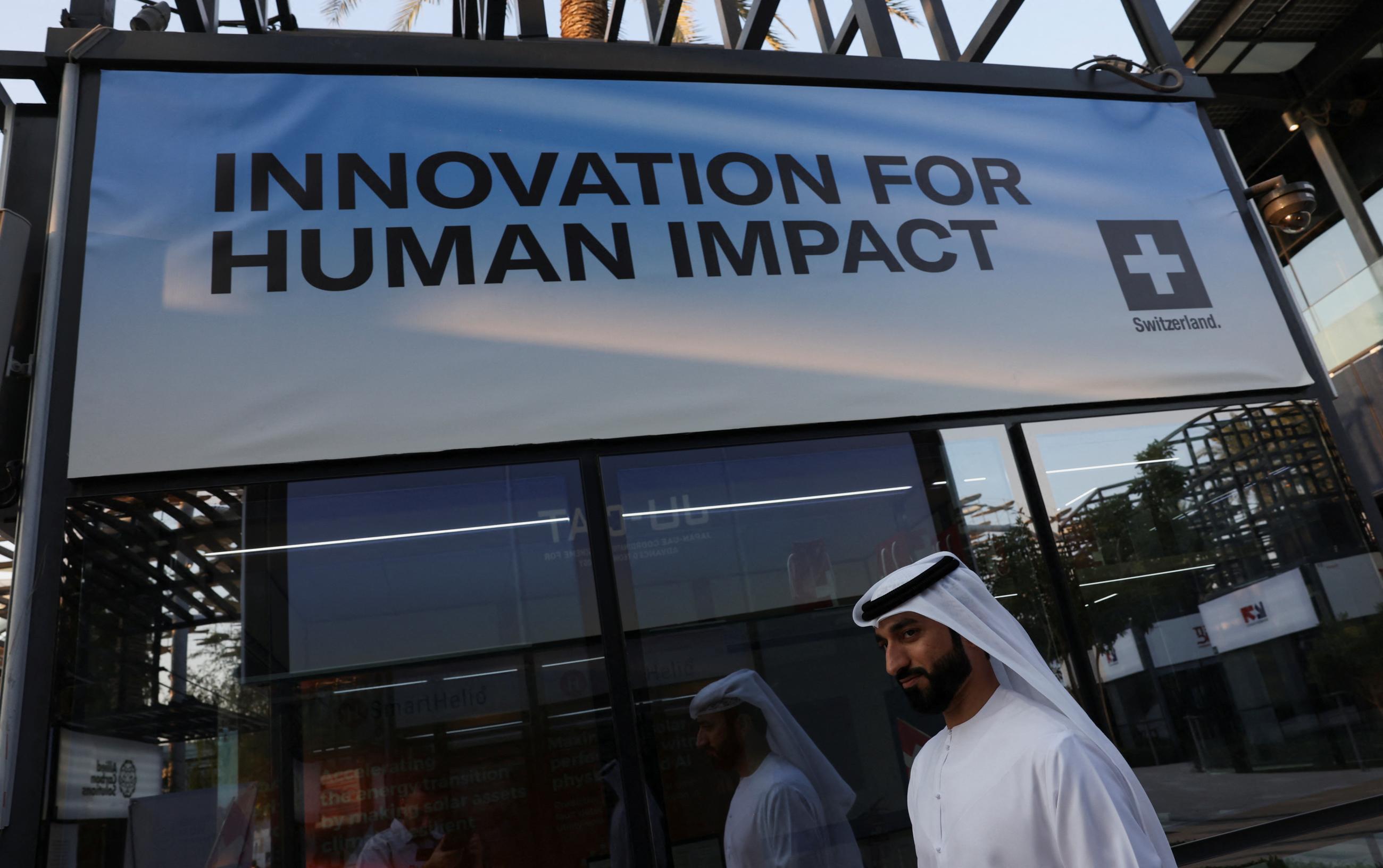 A person walks past a sign that reads "Innovation for Human Impact" during COP28.