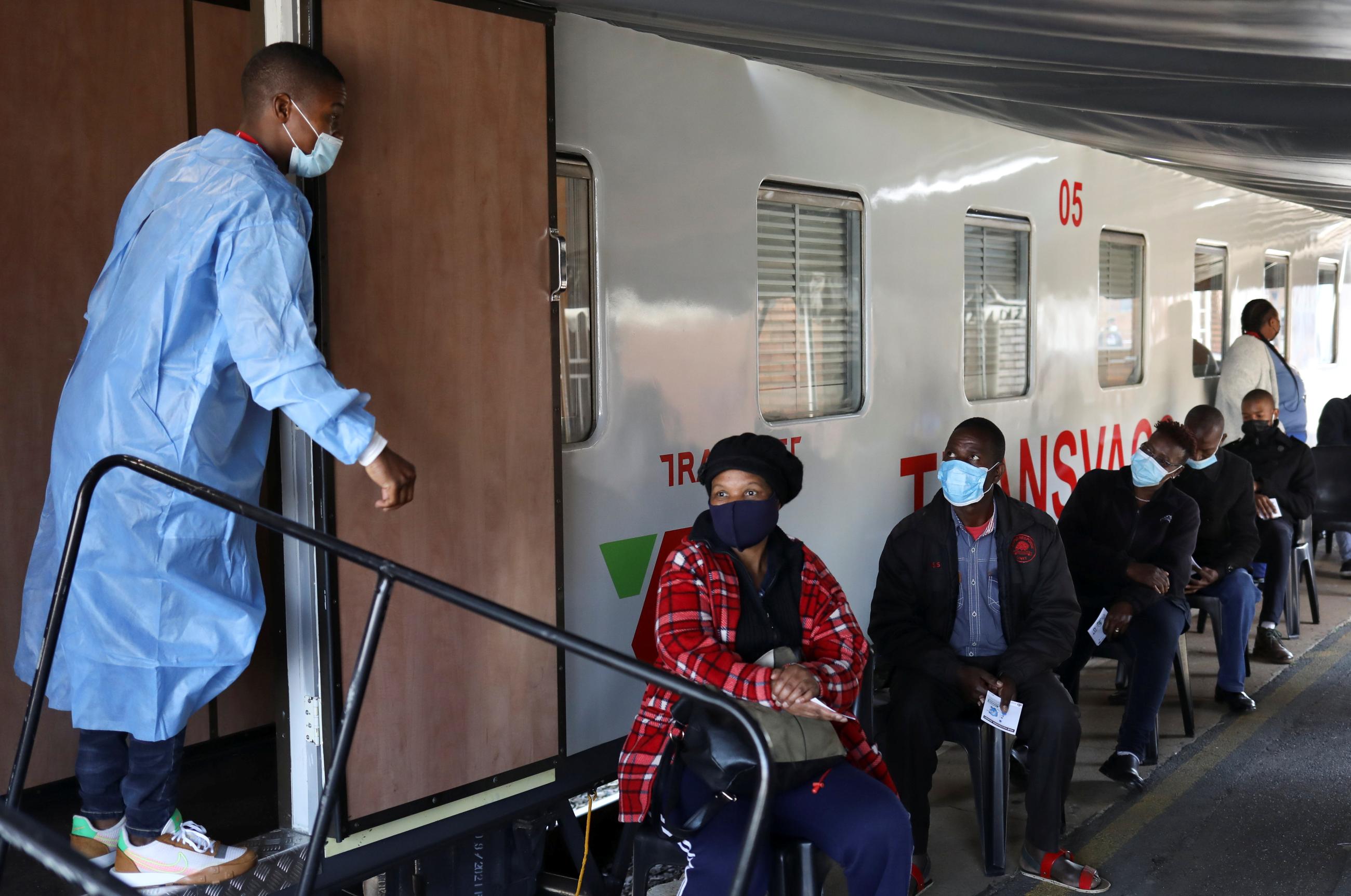 A health worker talks to people as they wait to register for the COVID-19 vaccine.