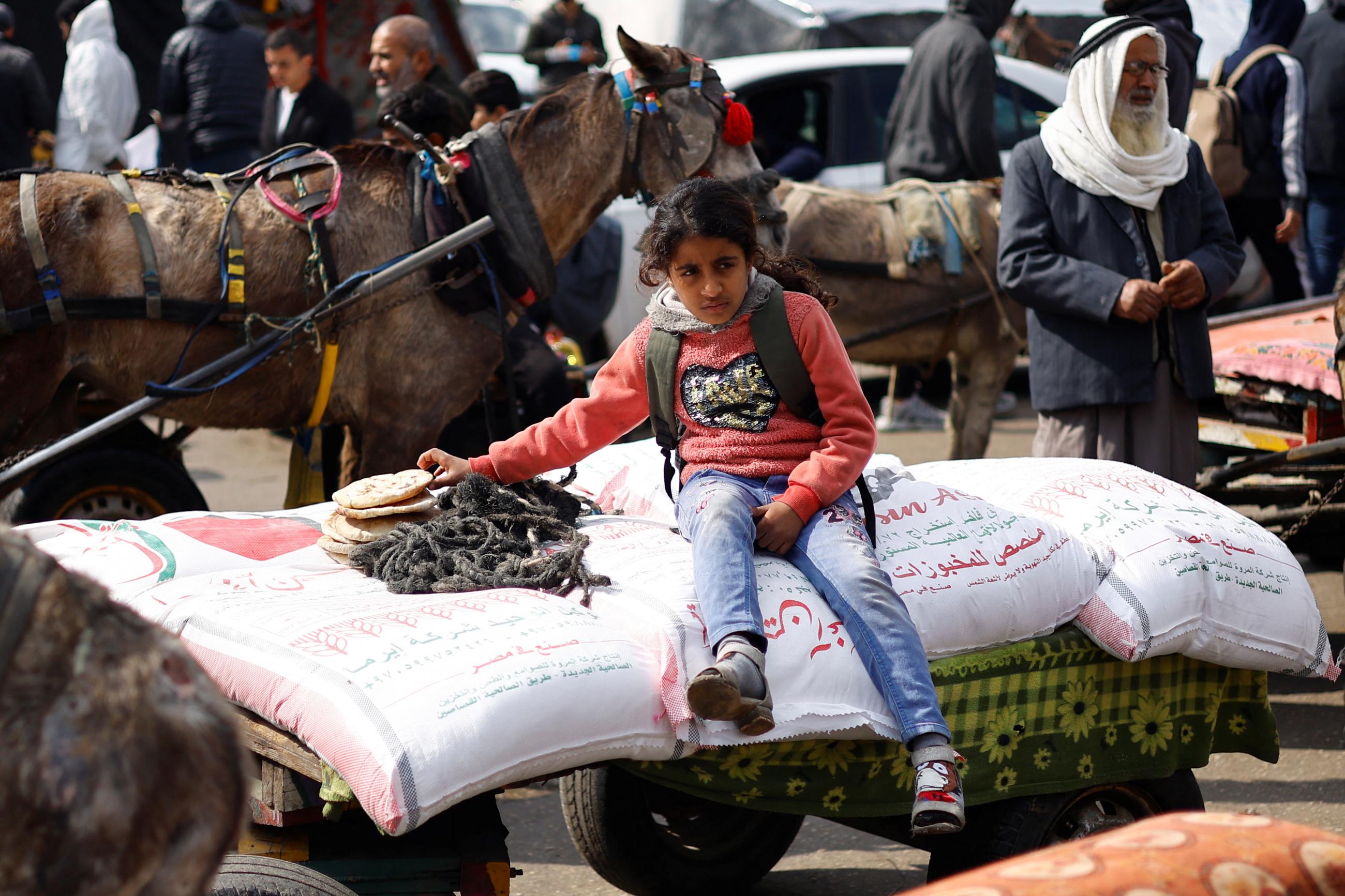 A Palestinian girl sits on bags of flour distributed by the United Nations Relief and Works Agency.
