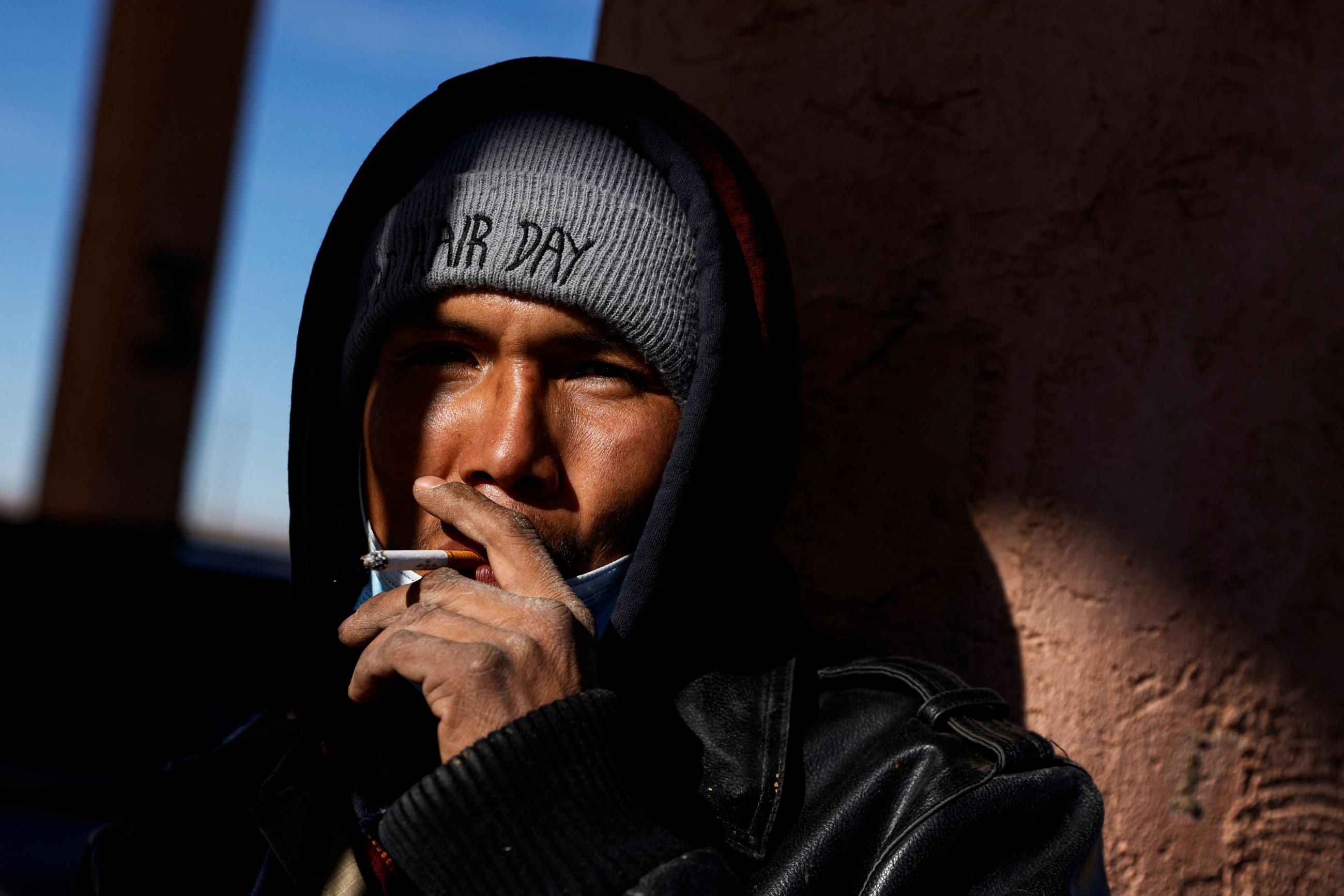 A man smokes a cigarette outside.