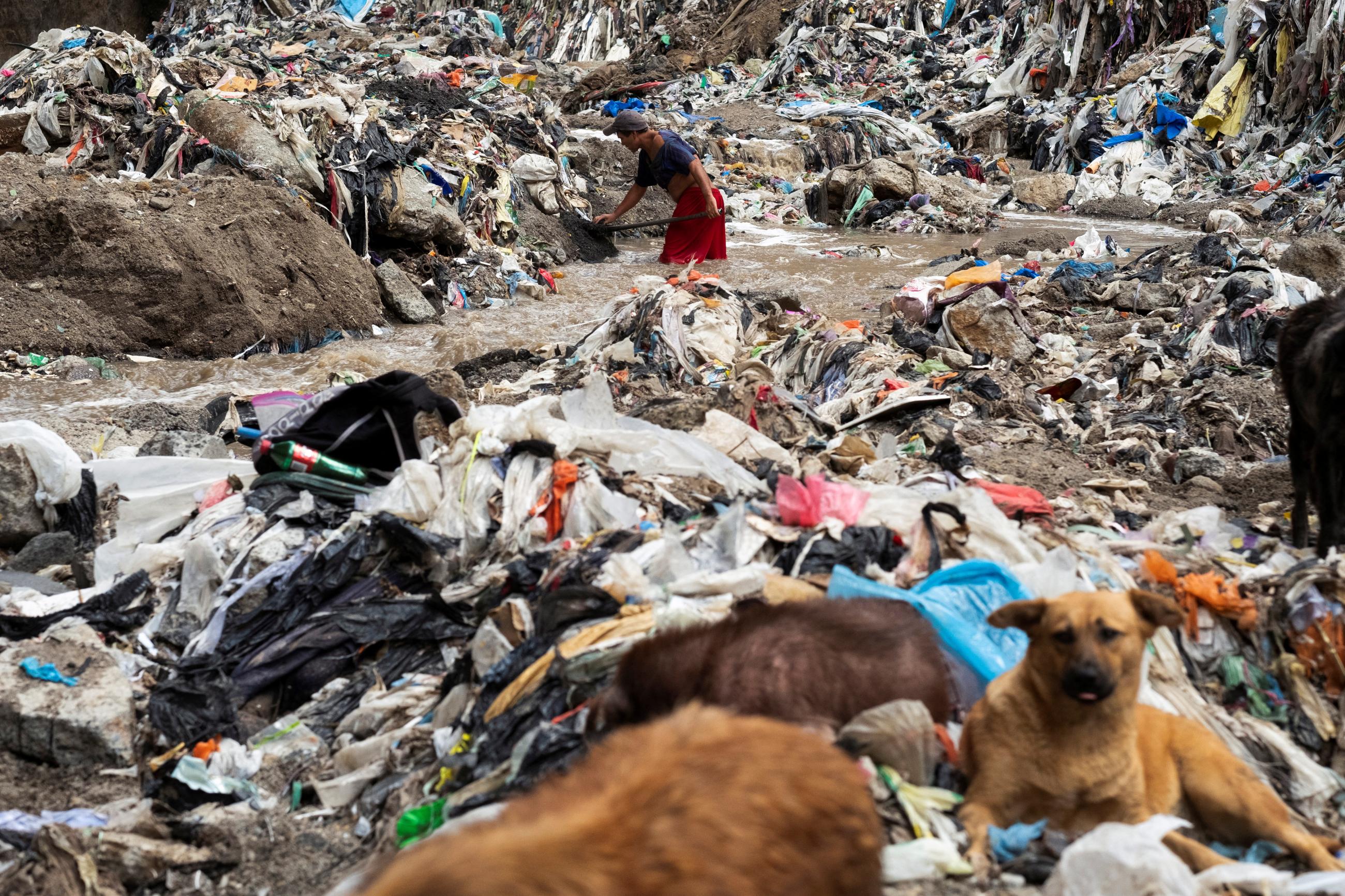 Man searches for scrap metal in the polluted waters of the Las Vacas river, where informal workers salvage items from Guatemala's largest landfill, in Guatemala City, Guatemala, on March 21, 2023. 
