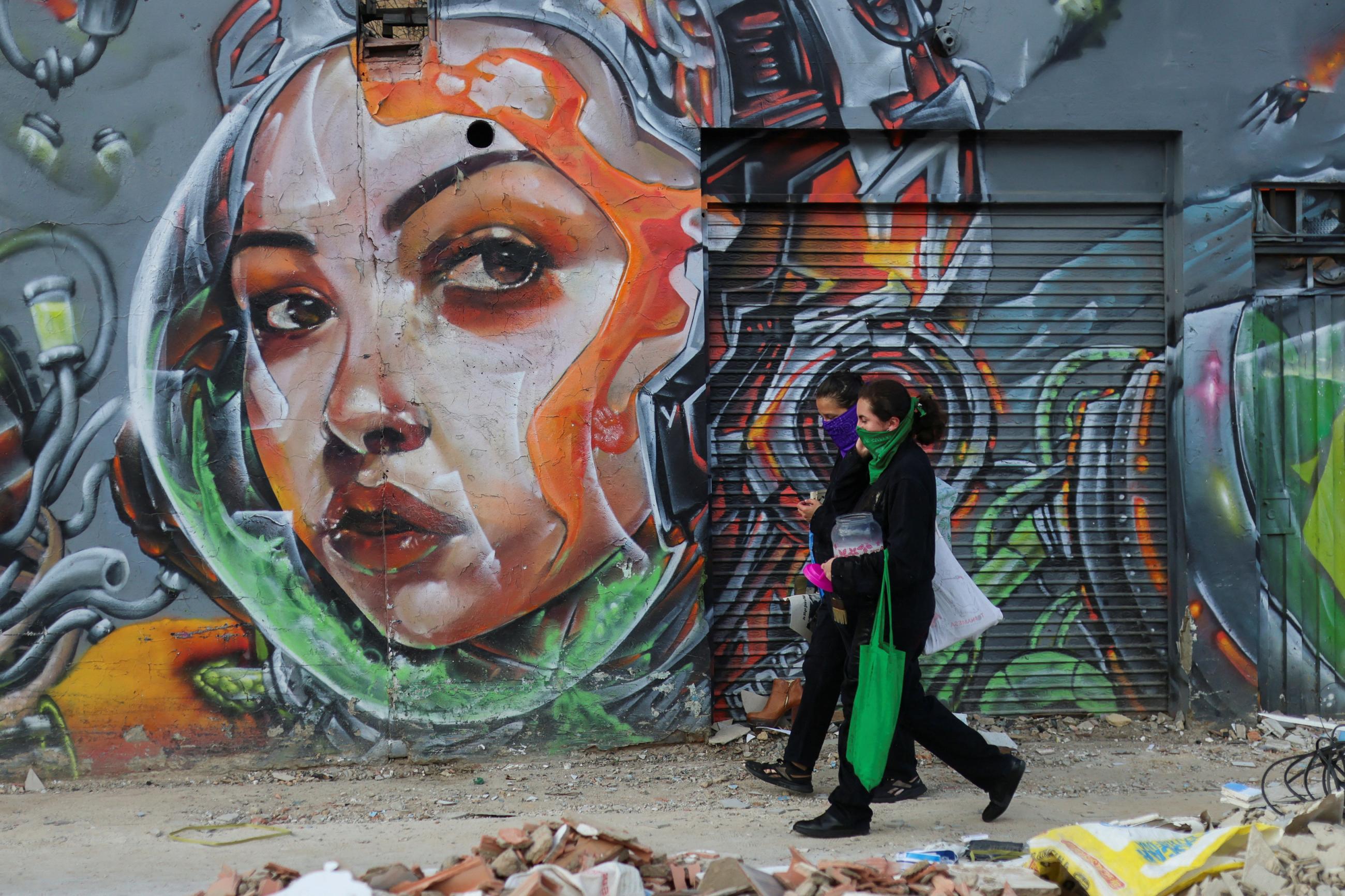 People pass a mural during a protest to mark the International Day for the Elimination of Violence against Women.