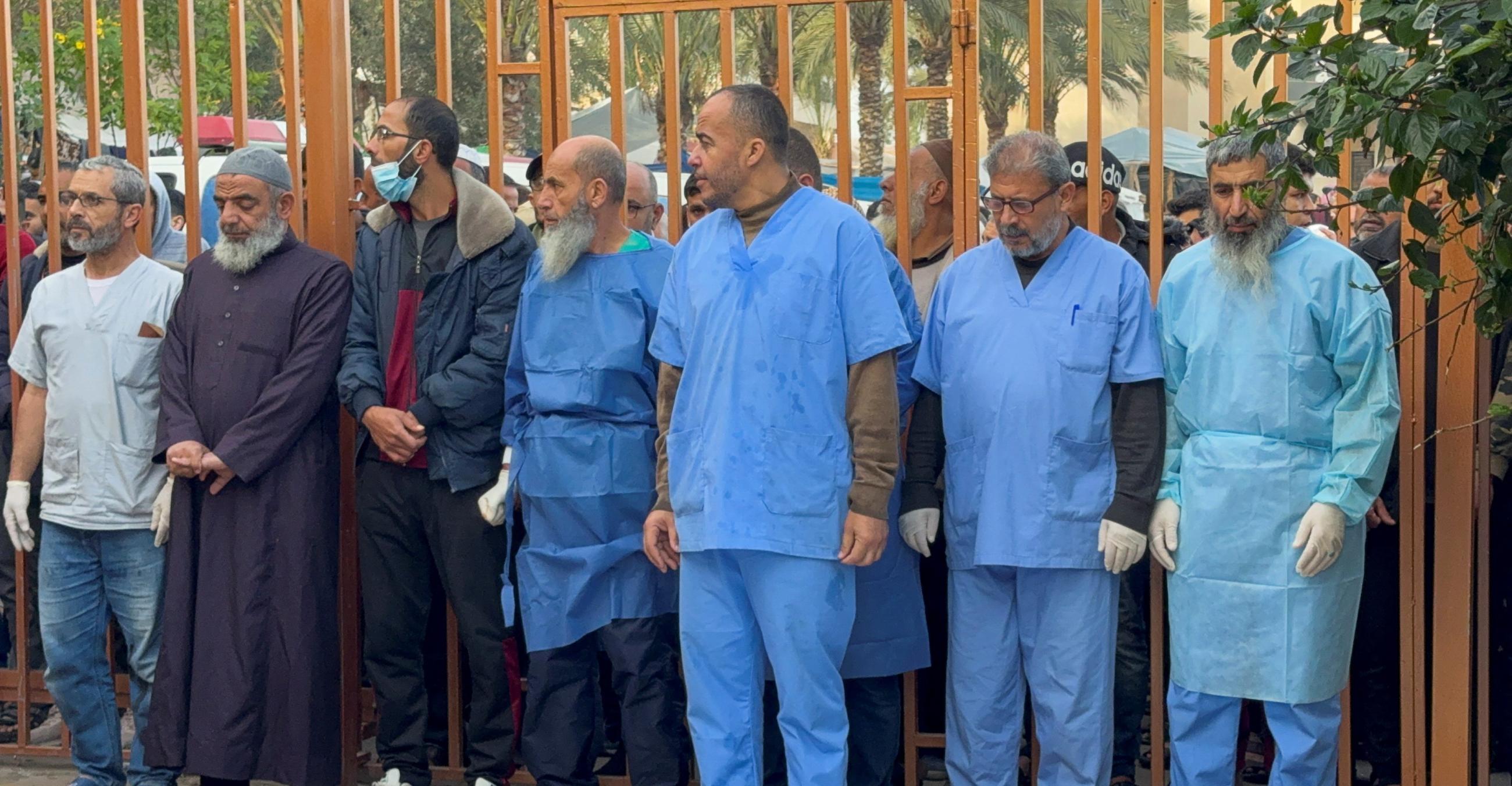 Medical staff stand by a gate.