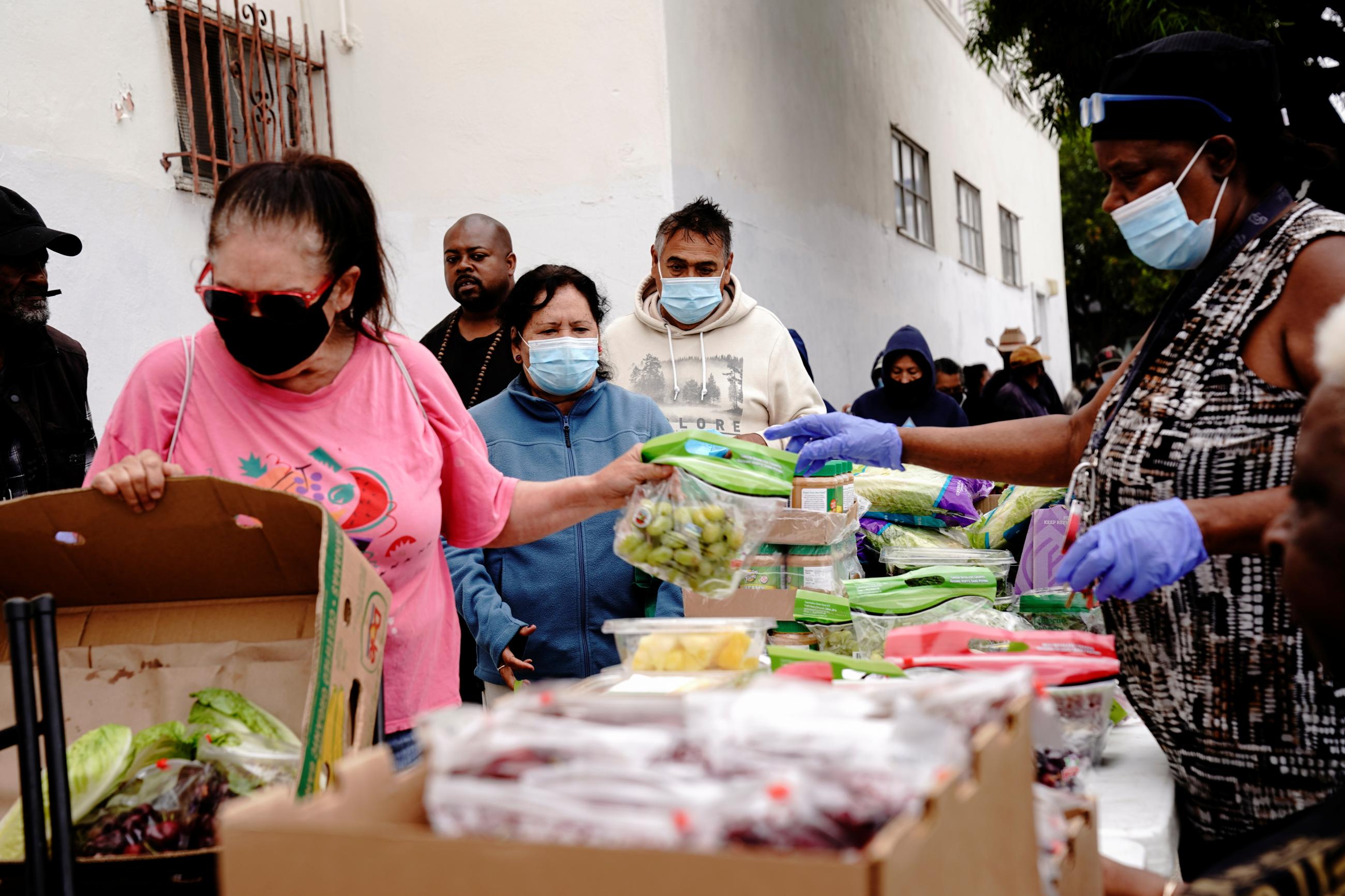 Volunteers distribute aid packages to people experiencing food insecurity at a give-away of food and baby formula.