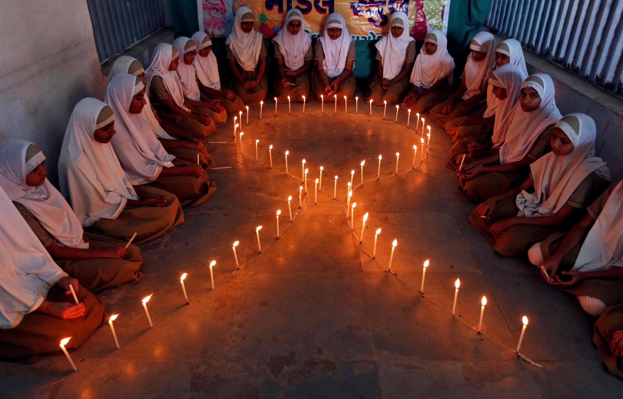 School girls light candles in the shape of a ribbon during a HIV/AIDS awareness campaign ahead of World Aids Day, in Ahmedabad, India November 30, 2016.