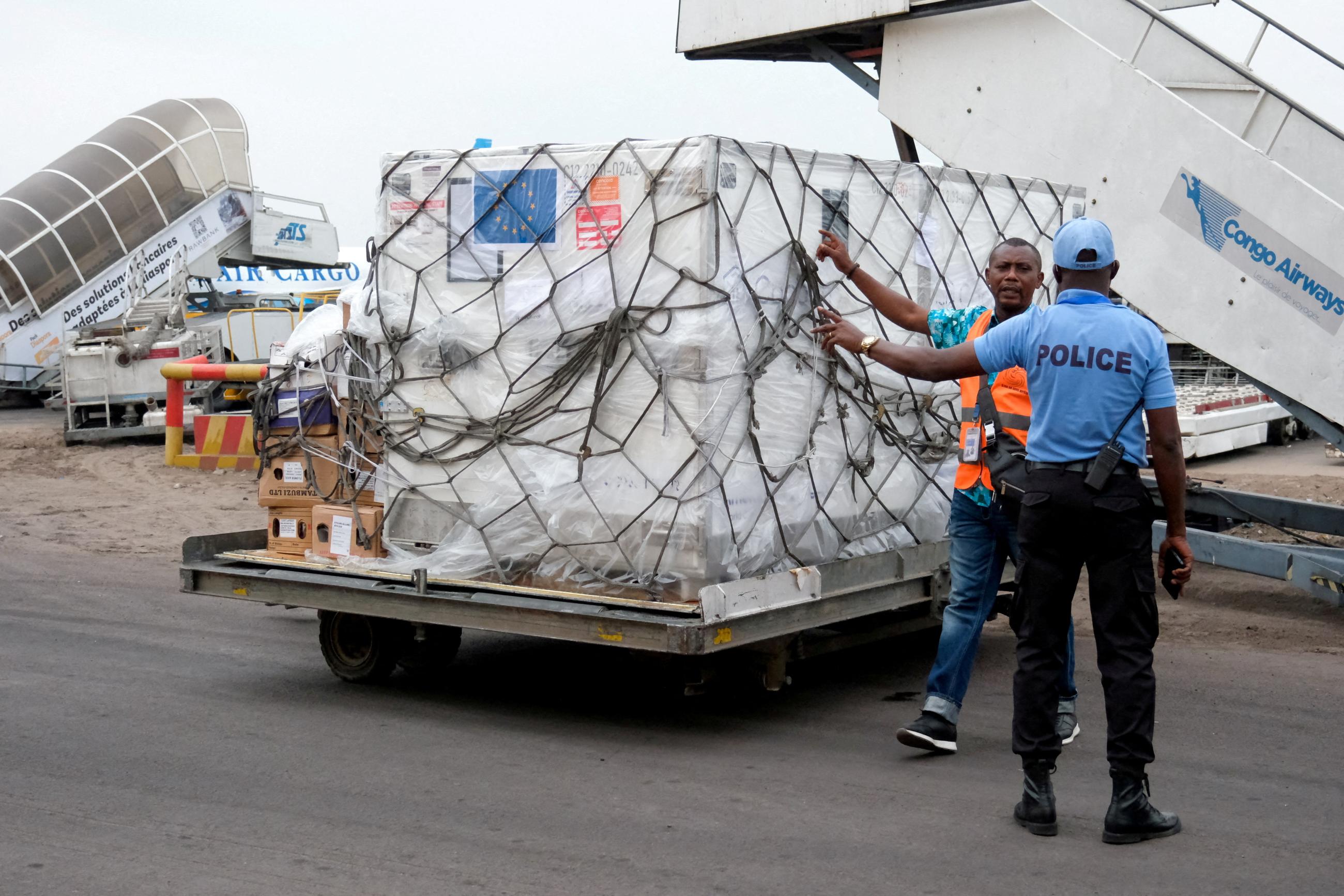 A security agent talks with a worker as he prepares to transport mpox vaccines as they arrive at N'Djili International Airport.