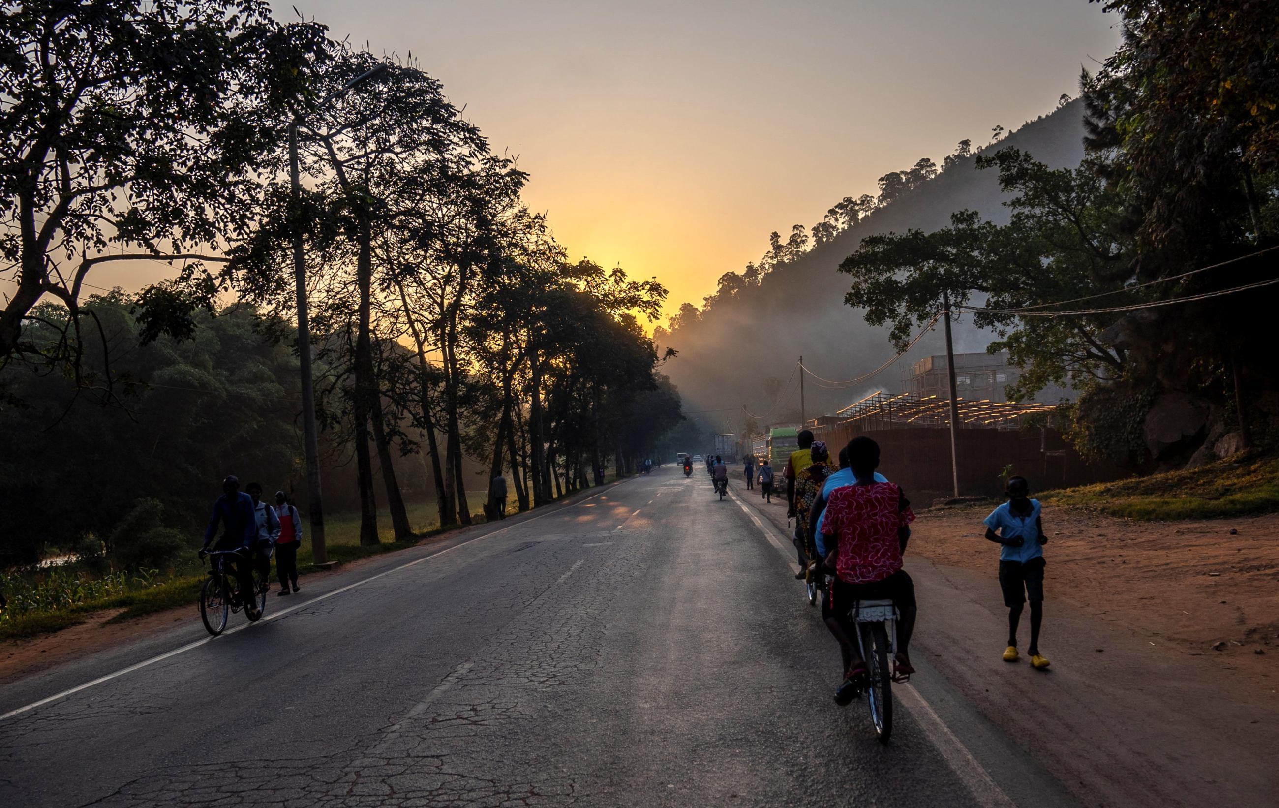 Residents cycle along a road at dawn, on the outskirts of Kigali, Rwanda, on June 15, 2022.