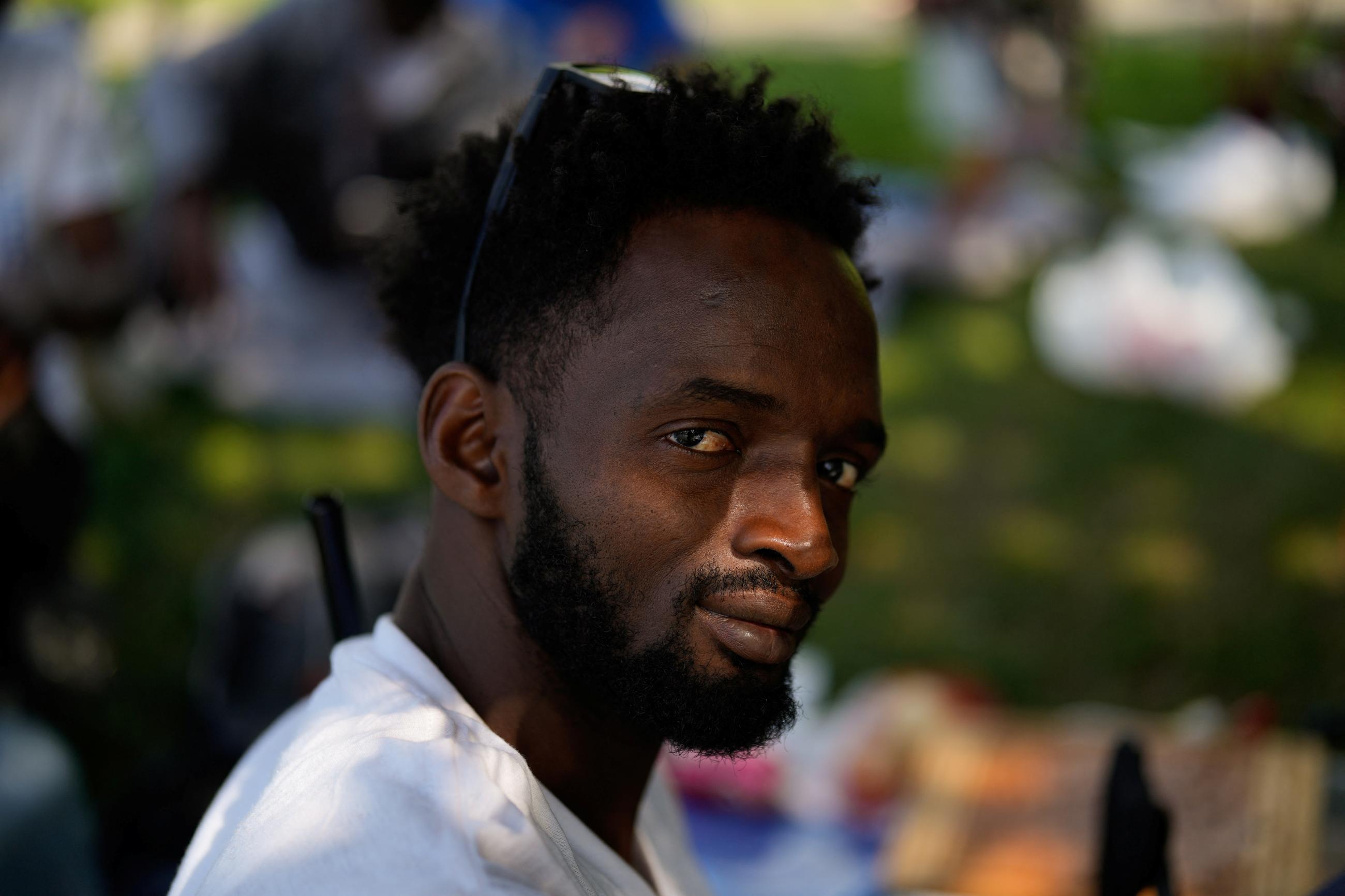 Usman Jalloh, a migrant from Guinea, poses for a portrait as he camps near a temporary shelter on Randall's Island.