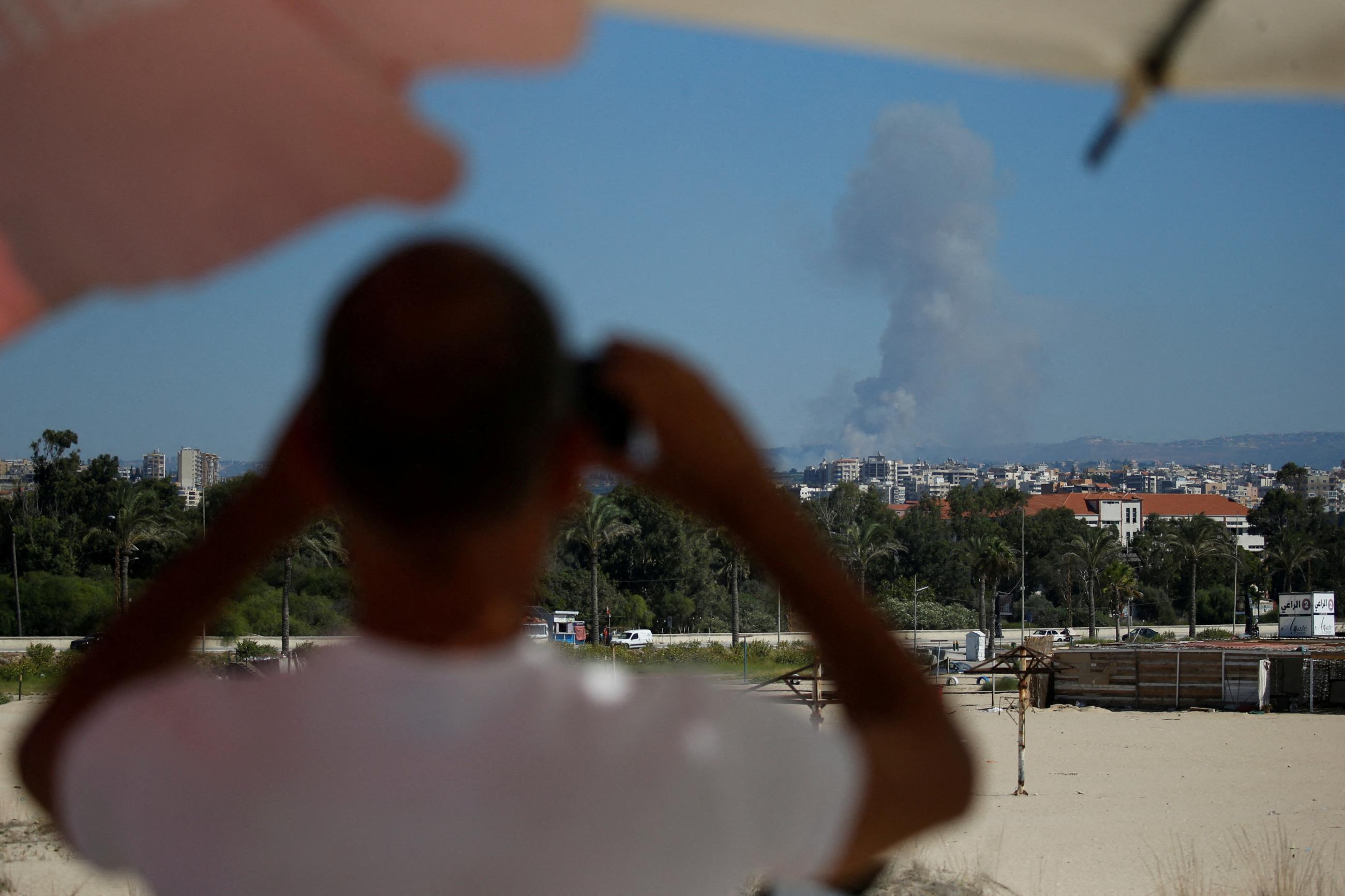A man watches as smoke billows over southern Lebanon following an Israeli strike, amid ongoing cross-border hostilities between Hezbollah and Israeli forces, as seen from Tyre, Lebanon September 26, 2024.