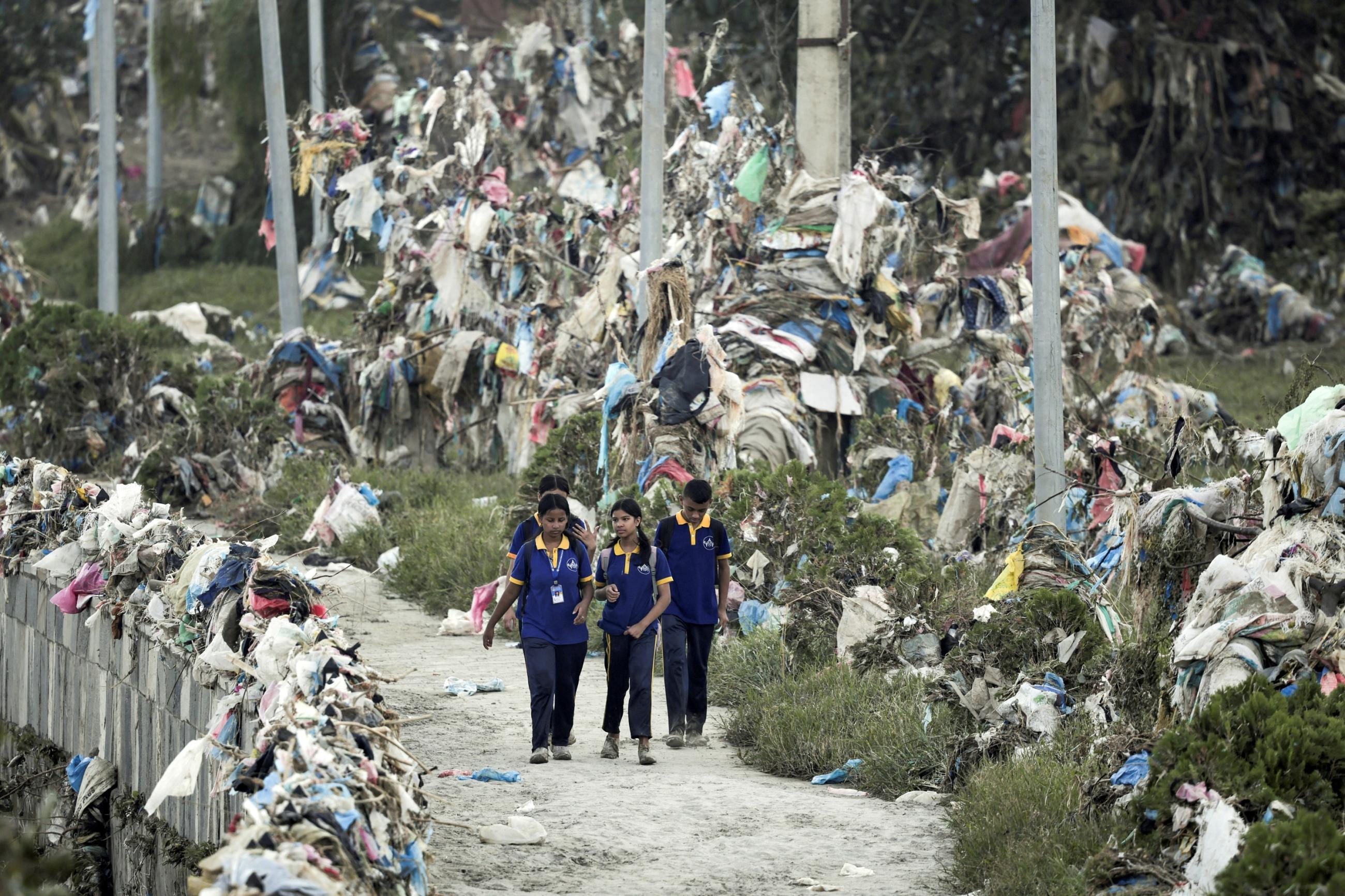 Students walk past the debris, mostly plastic waste dumped into the Bagmati river, as flood waters recede from its banks following heavy rains in Kathmandu, Nepal, October 2, 2024.