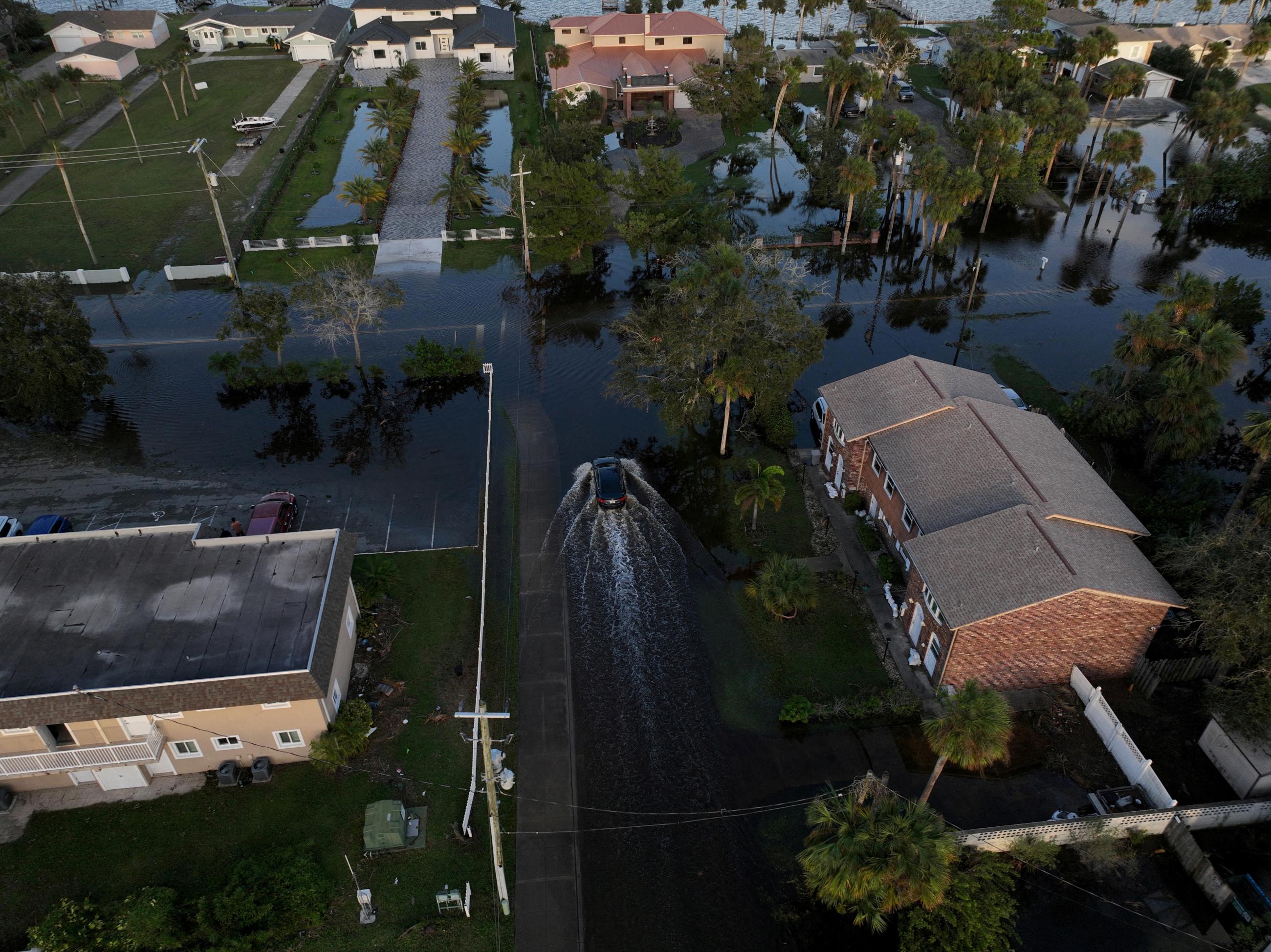 A drone view shows a car driving through a flooded street after Hurricane Milton made landfall.