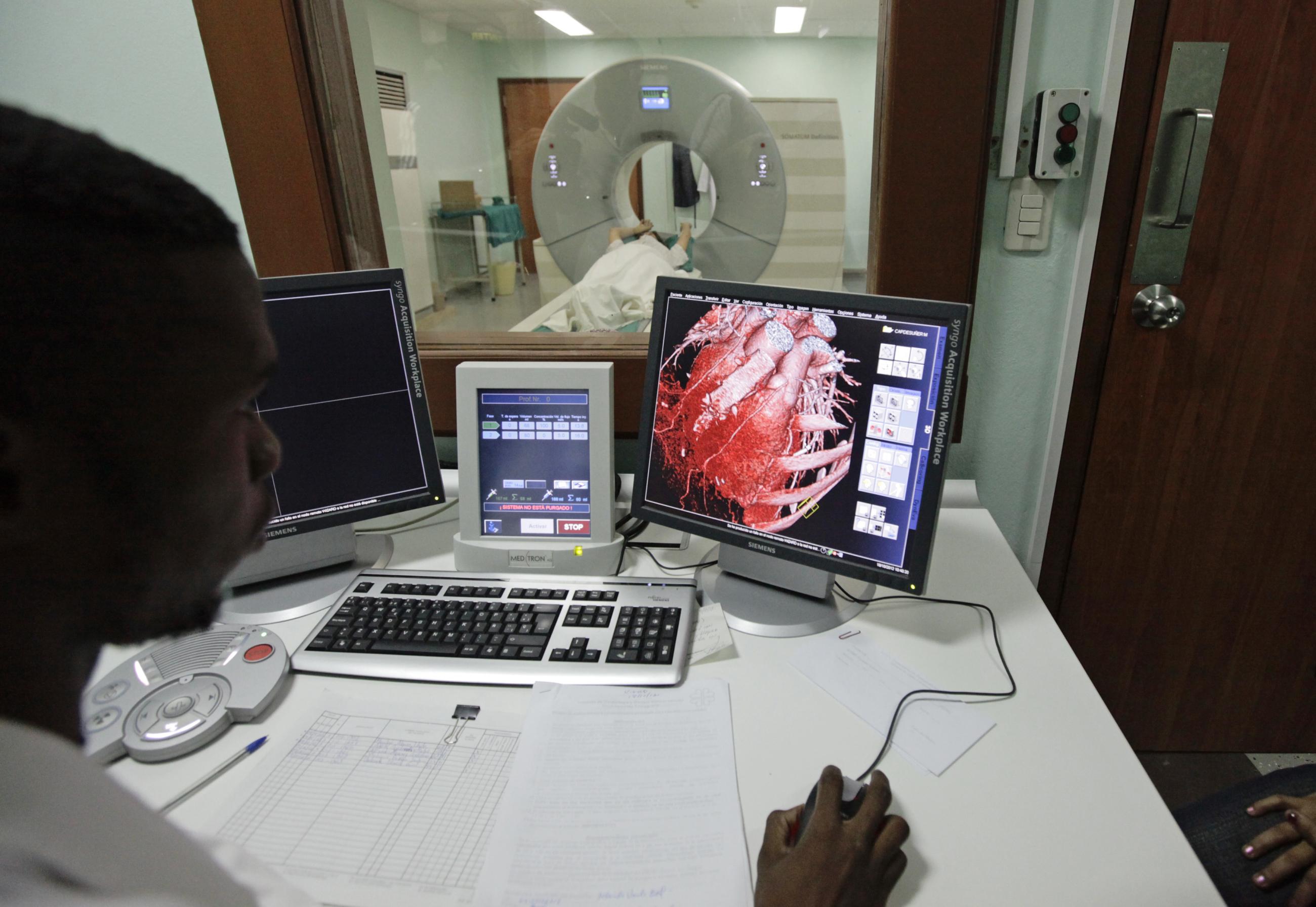 A doctor observes a screen showing a graphical representation of a heart after a full-body scan.