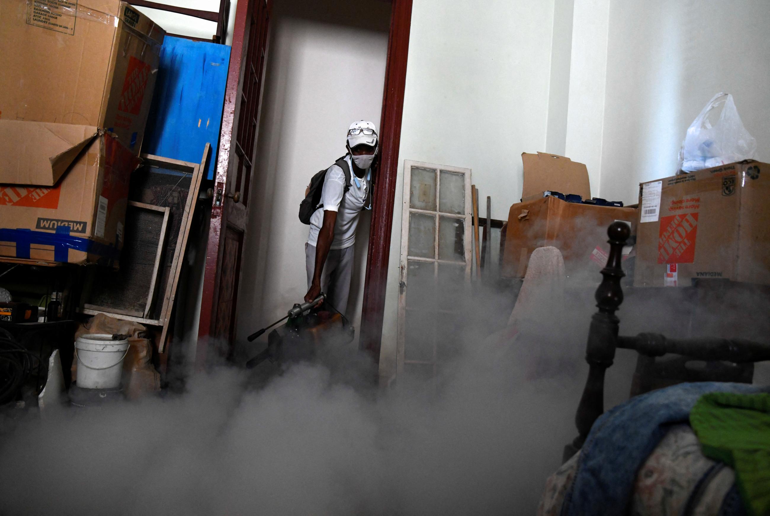 A health worker fumigates the bedroom in an apartment as health authorities launched small-scale fumigation efforts to fight the spread of the oropouche virus.