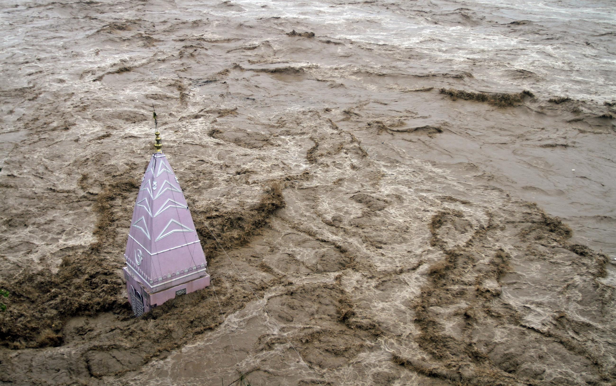 A temple stands amid the waters of the overflowing river Tawi during heavy rains in Jammu September 6, 2014. 