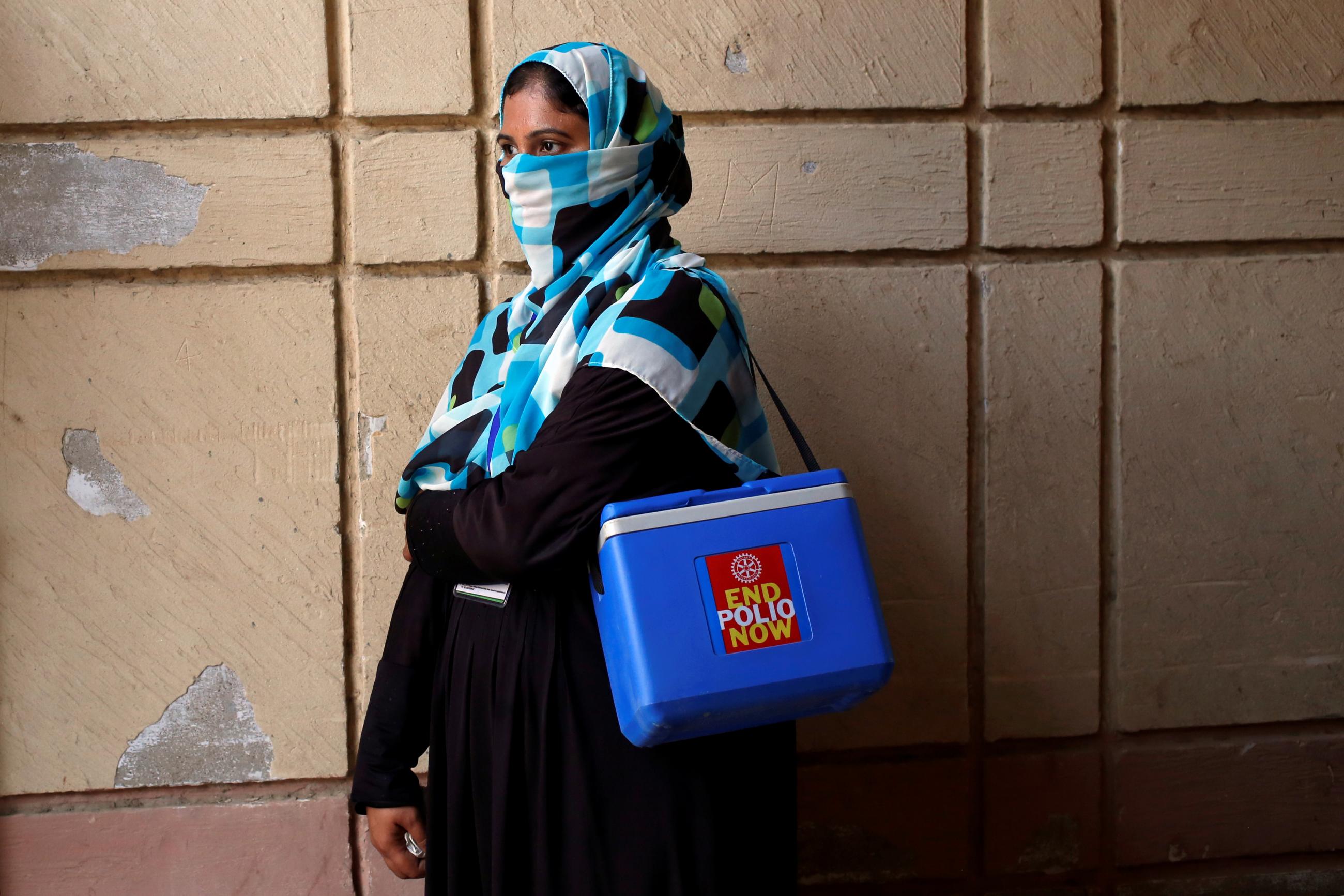 A vaccinator is seen with a kit box as she waits for her colleagues, to do an anti-polio campaign in a low-income neighborhood in Karachi, Pakistan, on April 9, 2018.
