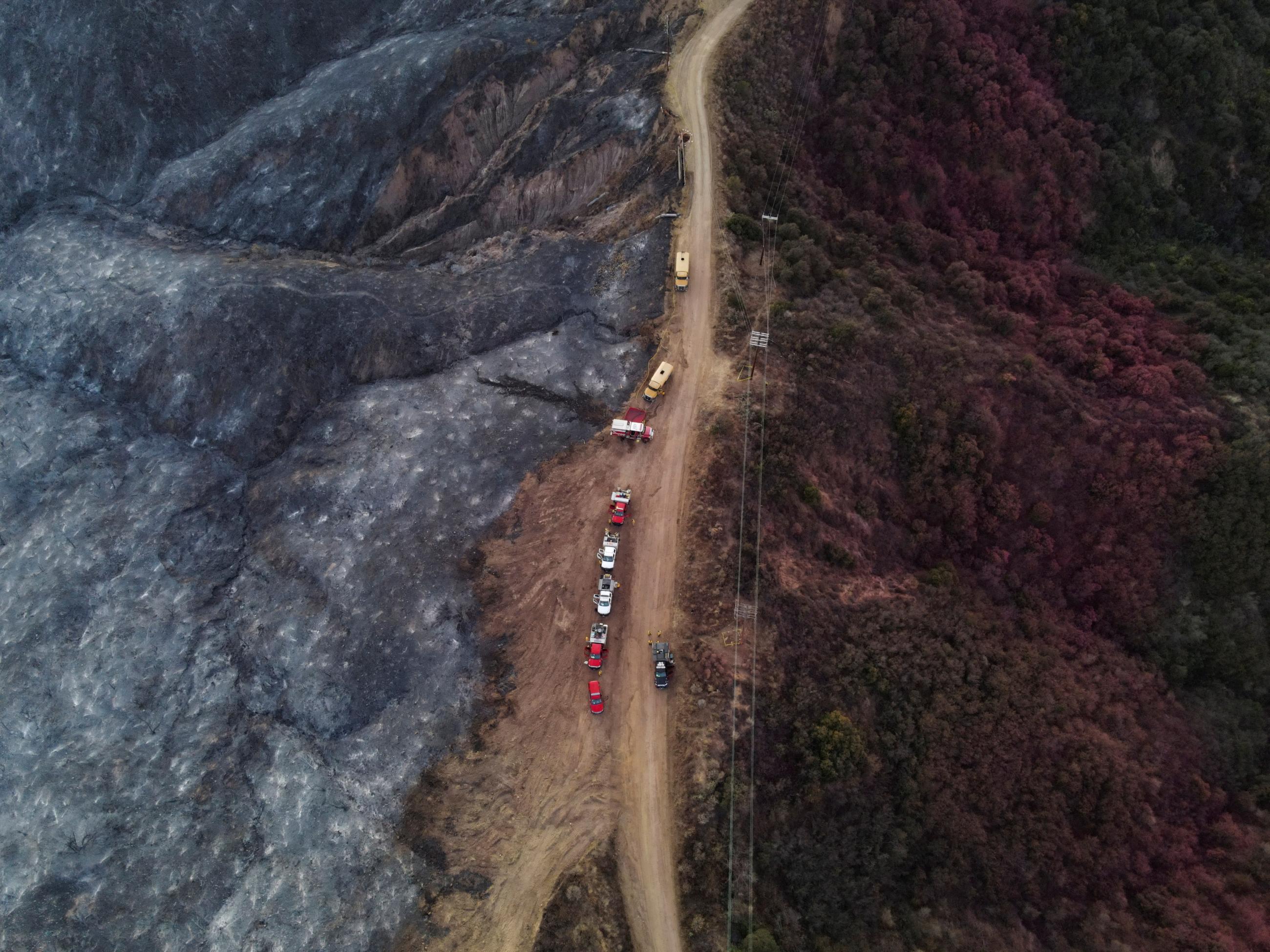 A drone view shows a CalFire crew mopping up hotspots from the burn scar of the Palisades Fire near Mulholland Drive, in Los Angeles, California, on January 15, 2025.