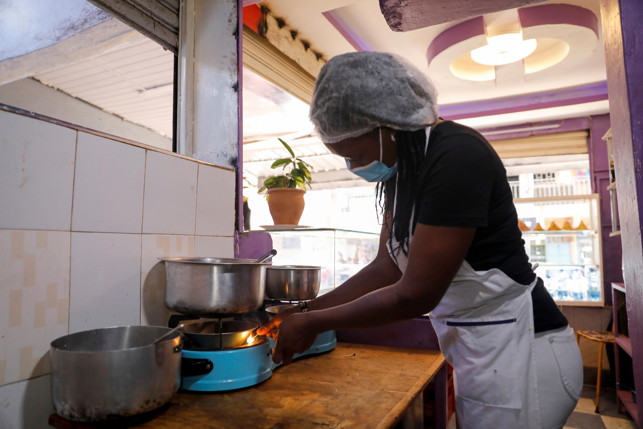 A woman cooks over a gas stove at a restaurant, using bioethanol fuel sold by the Koko startup company, in Nairobi, Kenya, on September 17, 2021.